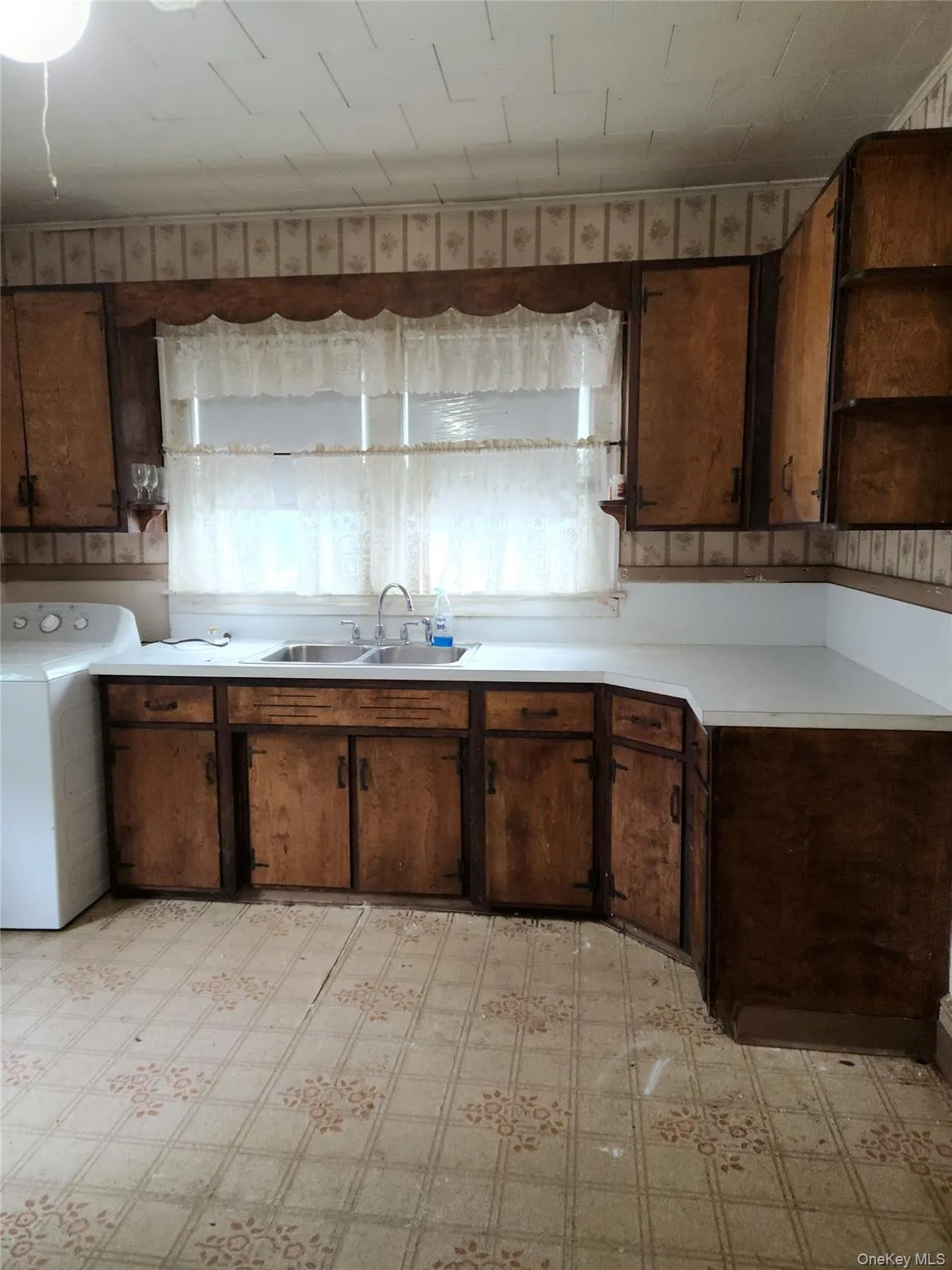 Kitchen featuring light countertops, open shelves, washer / clothes dryer, and light floors Kitchen featuring light countertops, open shelves, washer / clothes dryer, and light floors