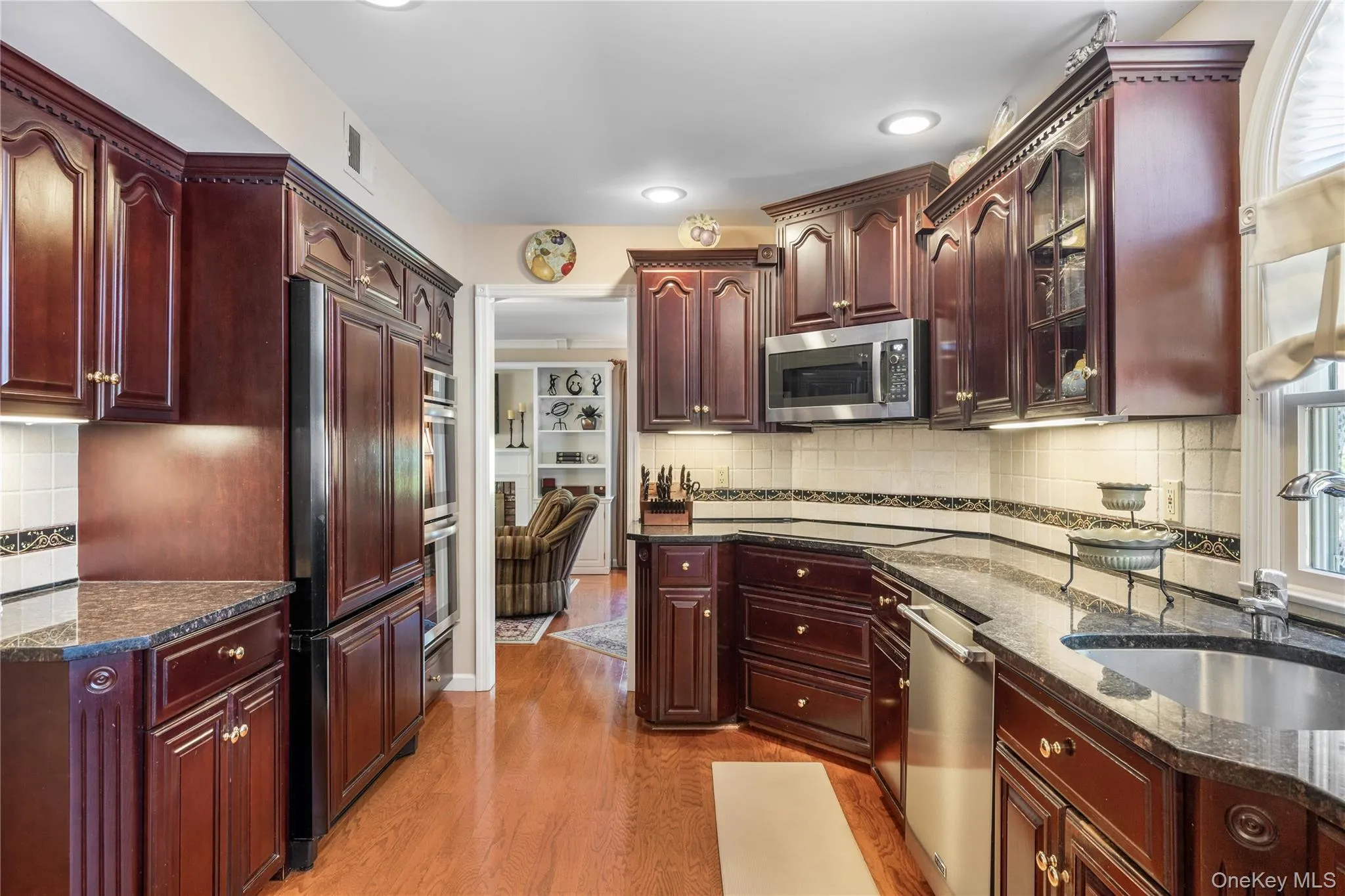 Kitchen featuring rich wood cabinetry, stainless steel appliances, granite countertops, and hardwood flooring Kitchen featuring rich wood cabinetry, stainless steel appliances, granite countertops, and hardwood flooring