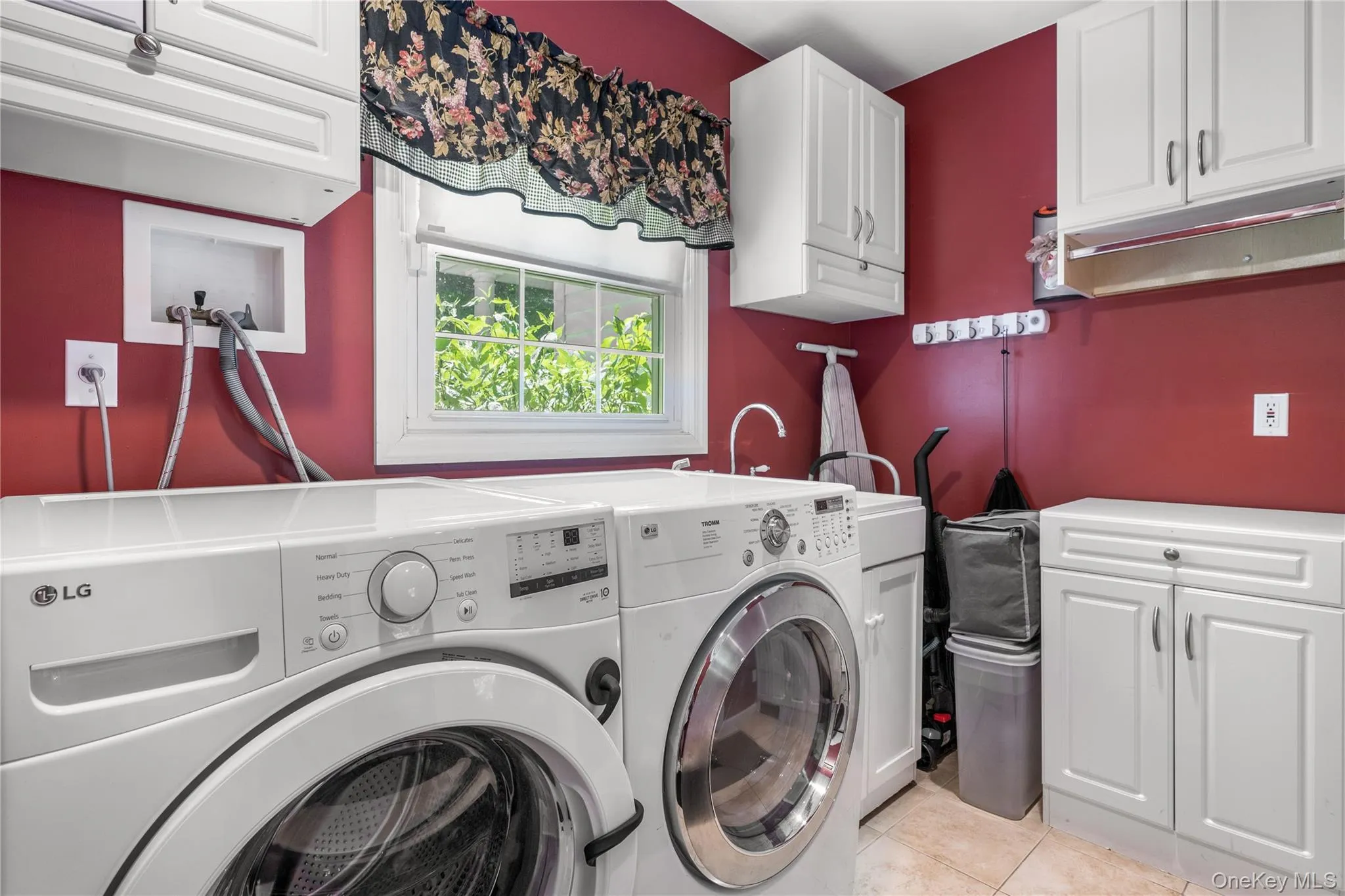 Dedicated laundry space featuring white cabinetry, a utility sink with a high-arc faucet, and tiled flooring Dedicated laundry space featuring white cabinetry, a utility sink with a high-arc faucet, and tiled flooring
