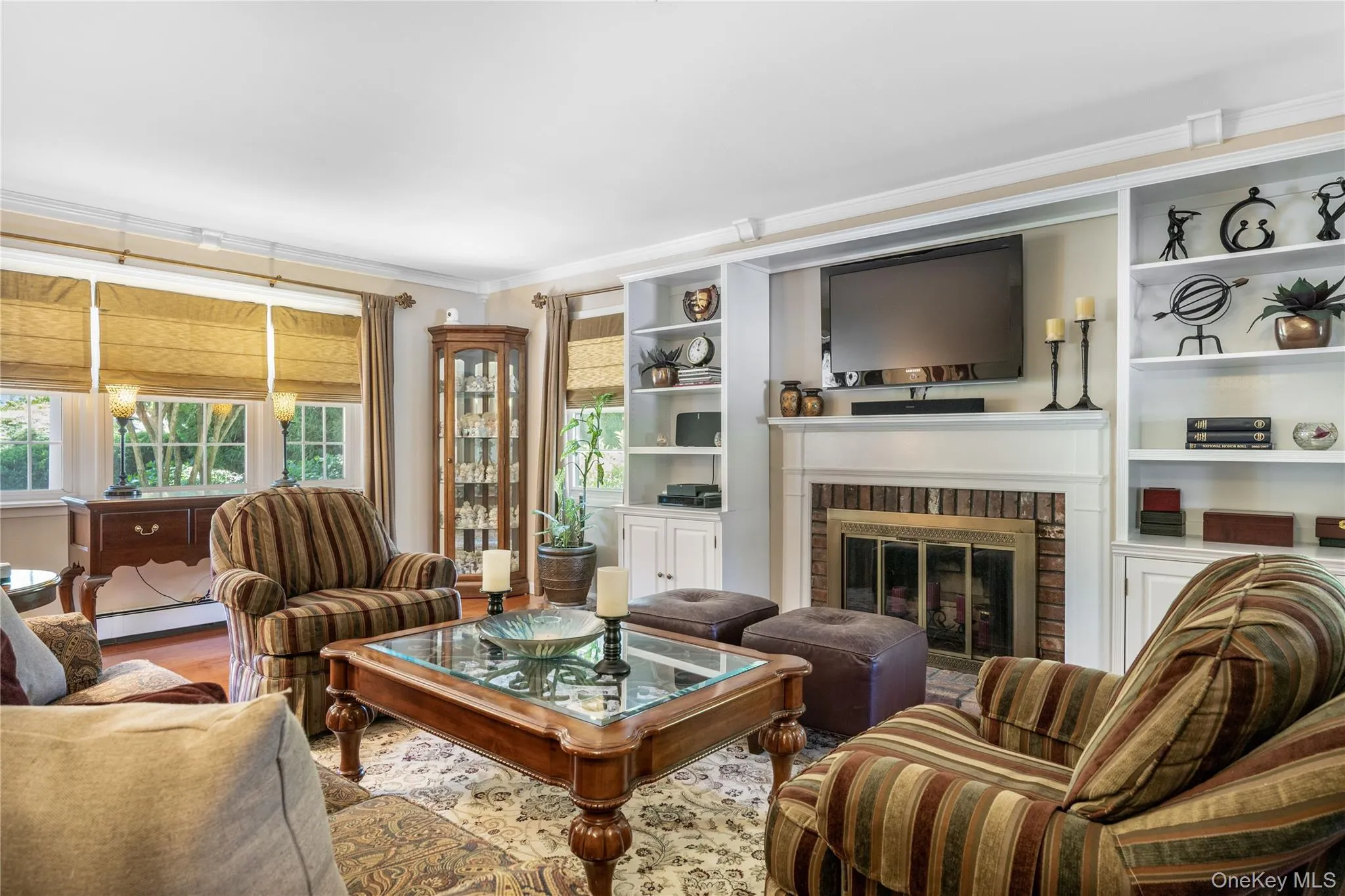 Living area featuring a brick fireplace with a white mantel, surrounded by built-in shelving and lower cabinetry Living area featuring a brick fireplace with a white mantel, surrounded by built-in shelving and lower cabinetry