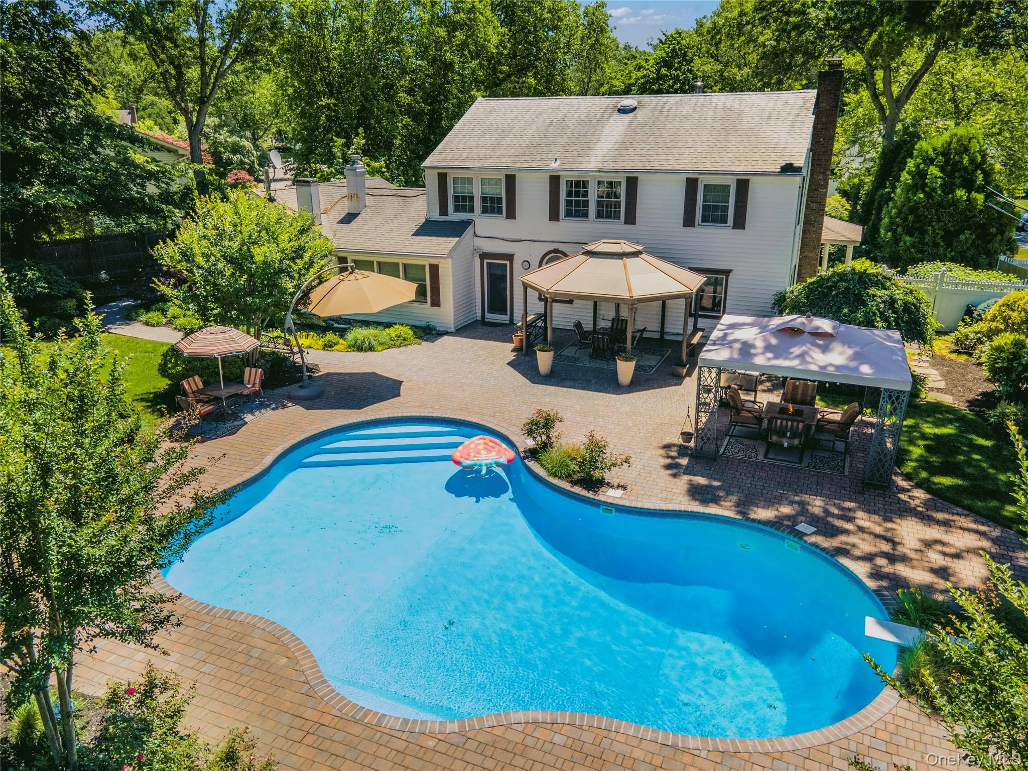 Expansive backyard featuring a freeform swimming pool with brick paver surround Expansive backyard featuring a freeform swimming pool with brick paver surround