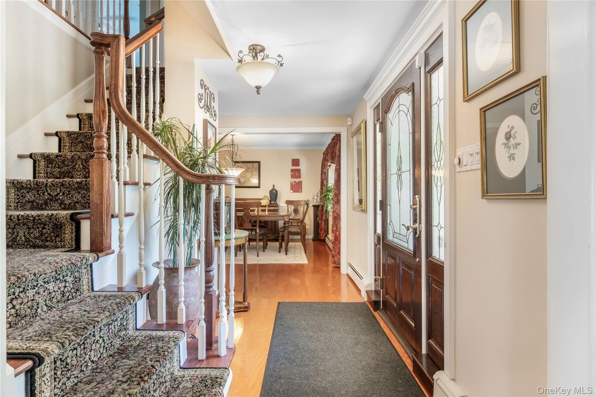 Entryway featuring a wood-finish staircase with carpet runner, hardwood flooring, and a decorative glass-paneled front door Entryway featuring a wood-finish staircase with carpet runner, hardwood flooring, and a decorative glass-paneled front door