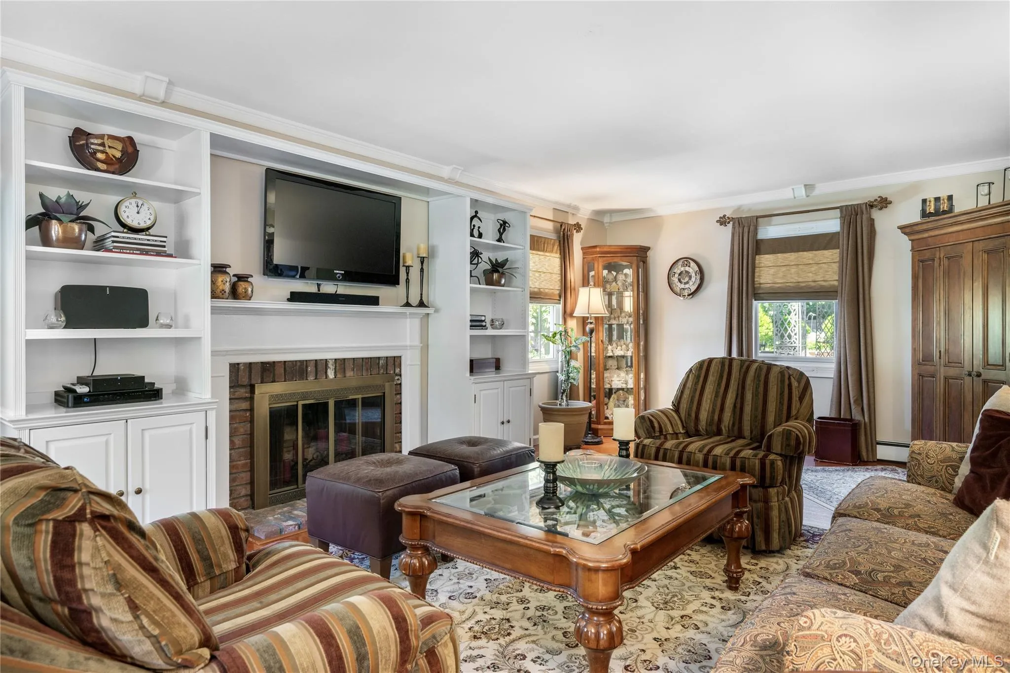 Living room featuring a brick fireplace with a white mantel, flanked by built-in white shelving Living room featuring a brick fireplace with a white mantel, flanked by built-in white shelving