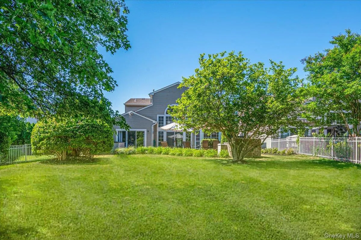 Expansive green lawn with mature trees and perimeter fencing Expansive green lawn with mature trees and perimeter fencing