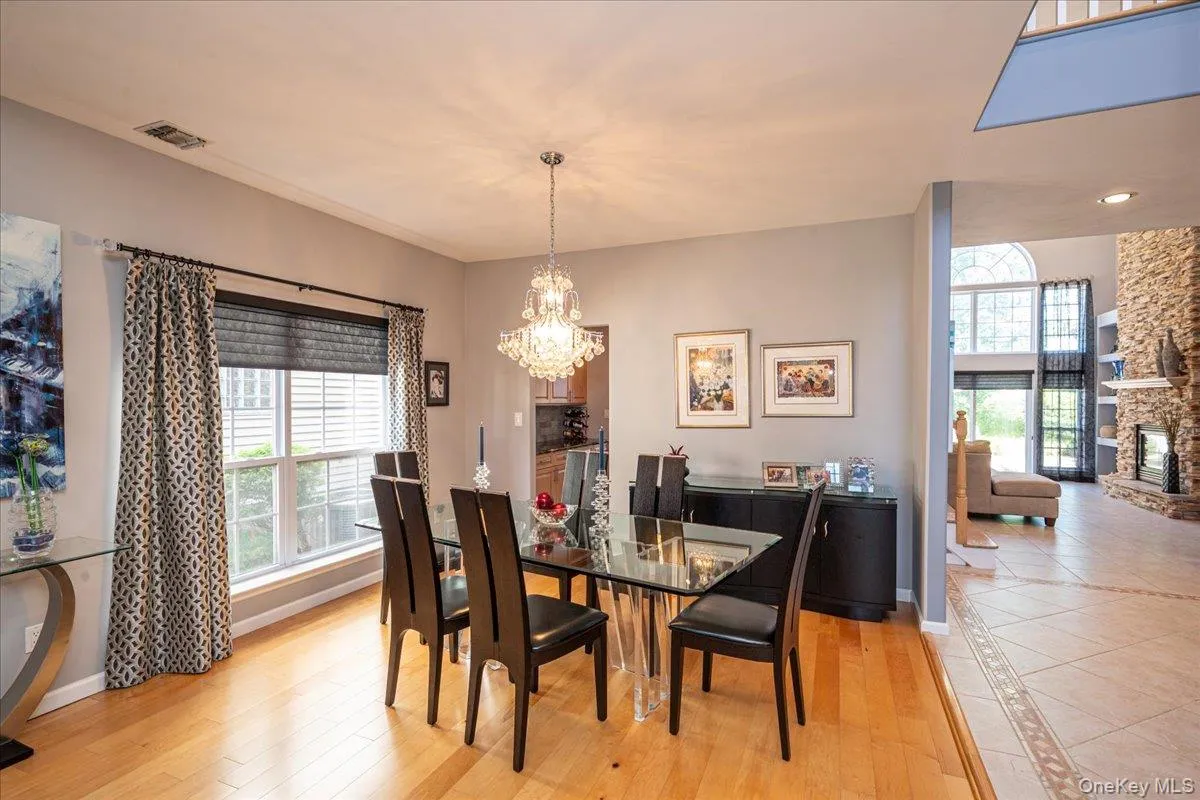 Dining area featuring hardwood flooring, a crystal chandelier, and a large window with blinds Dining area featuring hardwood flooring, a crystal chandelier, and a large window with blinds