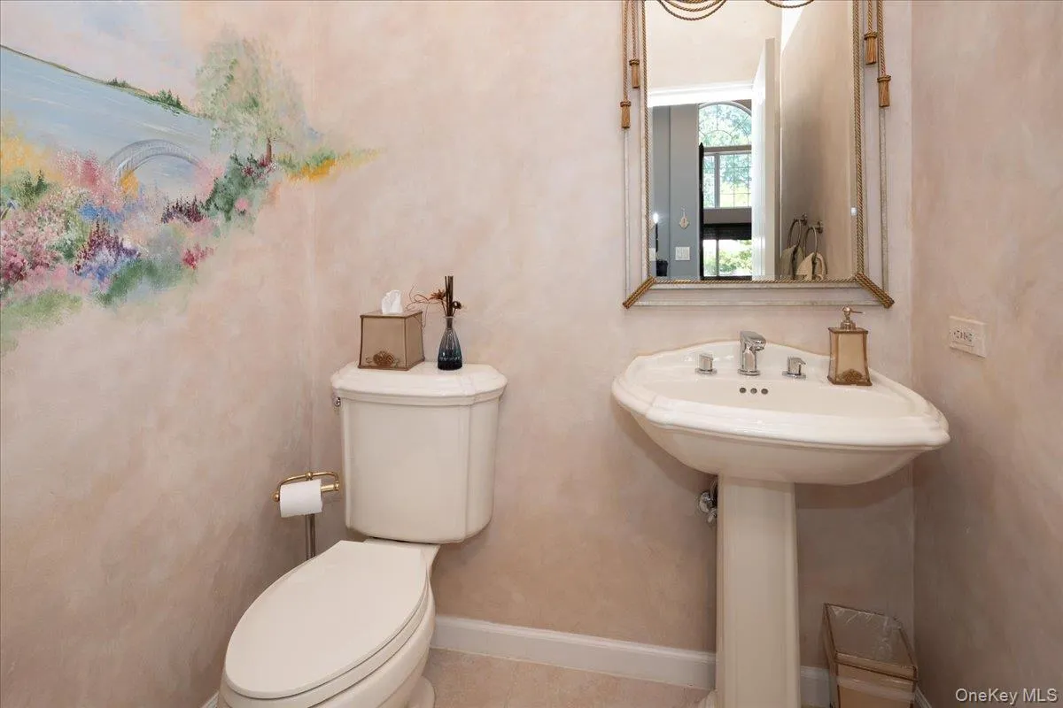 Pedestal sink with Powder Room with polished chrome faucet, framed mirror, and wall-mounted toilet Pedestal sink with Powder Room with polished chrome faucet, framed mirror, and wall-mounted toilet