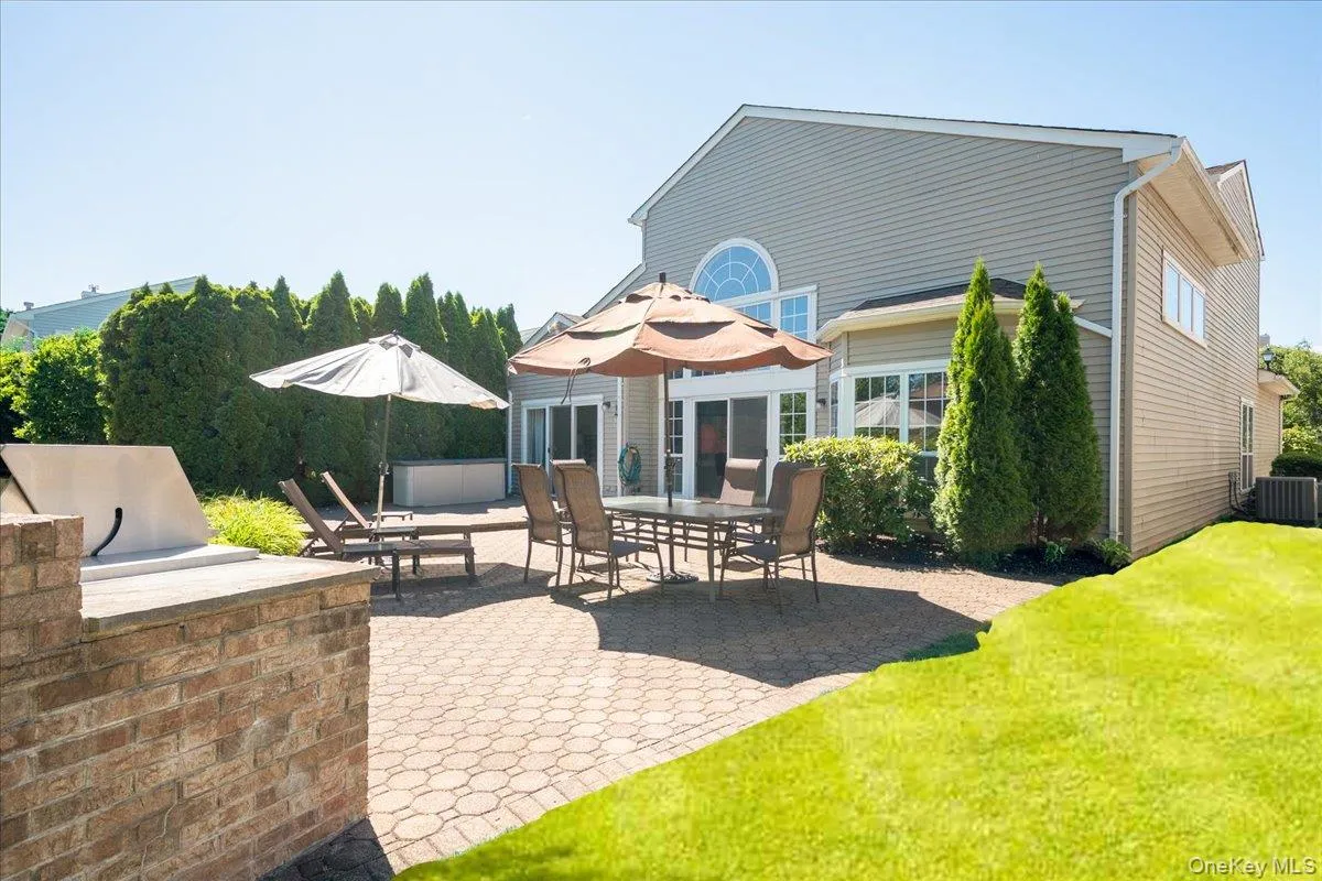 Expansive paver patio featuring a built-in brick grill station, multiple patio doors, and a decorative arched window Expansive paver patio featuring a built-in brick grill station, multiple patio doors, and a decorative arched window