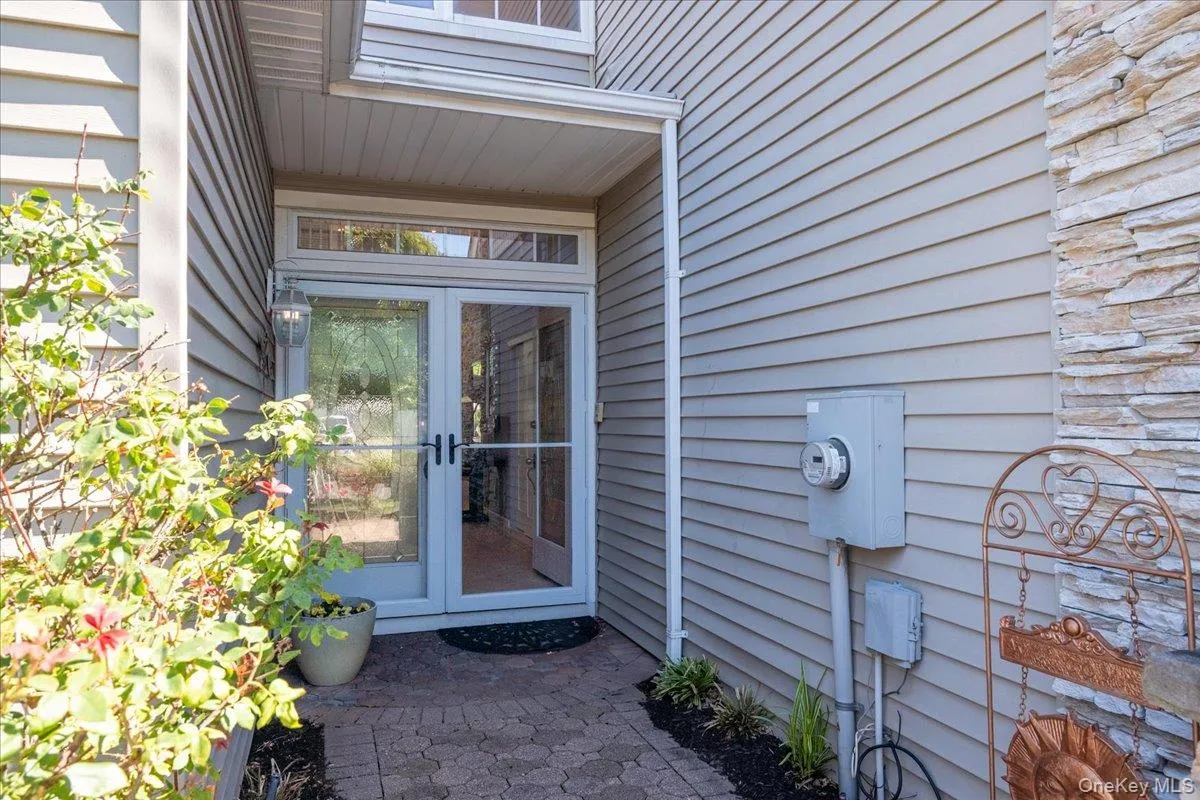 Entryway featuring a double glass storm door with transom window, stone veneer accent, horizontal siding, and a patterned paver pathway Entryway featuring a double glass storm door with transom window, stone veneer accent, horizontal siding, and a patterned paver pathway