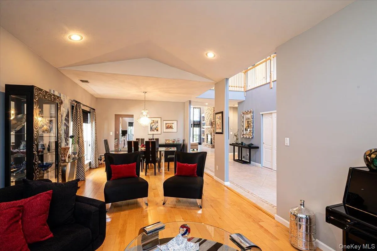 Living area featuring wood-finish flooring, recessed lighting, and a vaulted ceiling Living area featuring wood-finish flooring, recessed lighting, and a vaulted ceiling