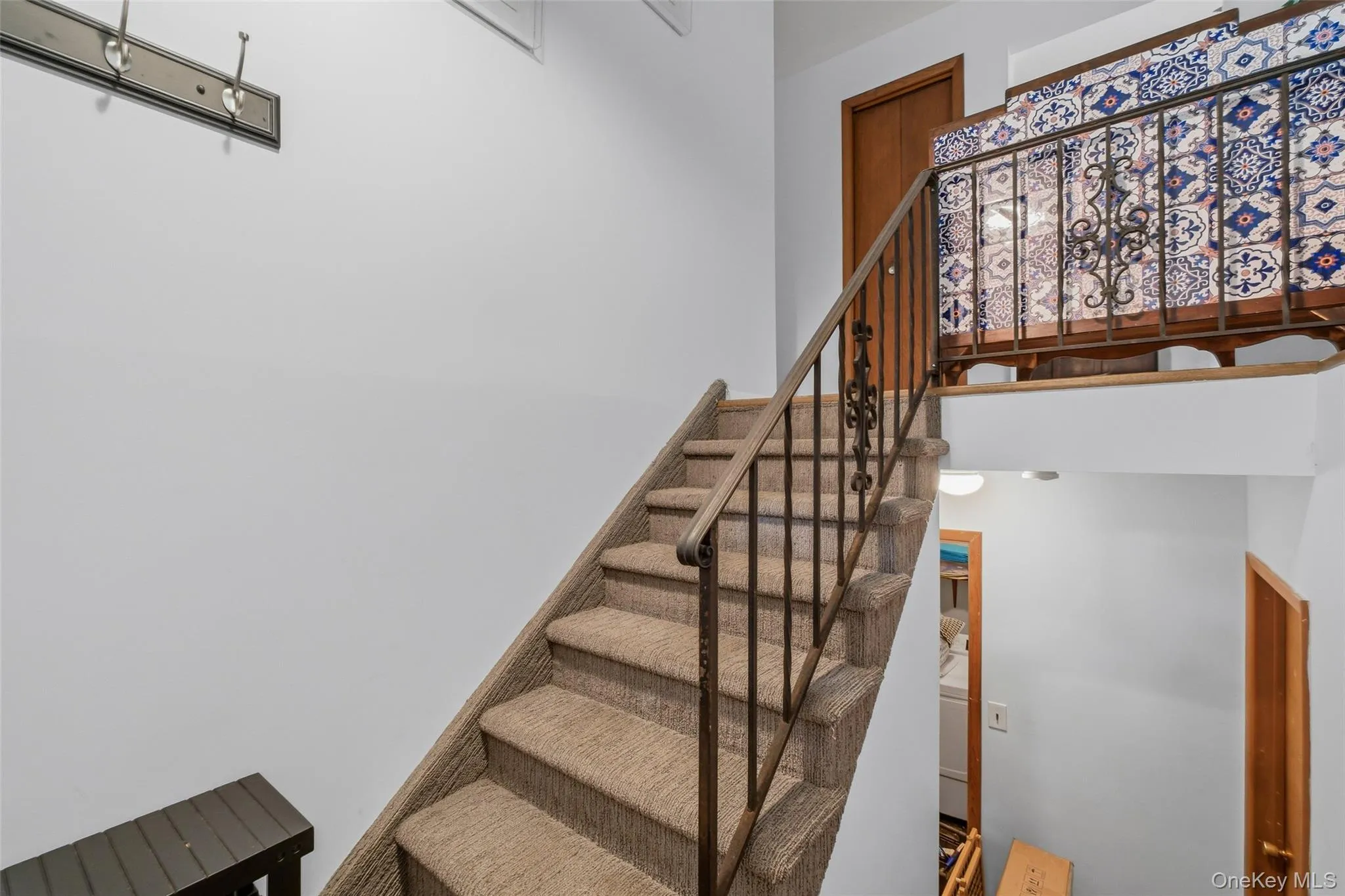 Carpeted staircase with wrought iron railing featuring ornate detailing leading to main and lower level Carpeted staircase with wrought iron railing featuring ornate detailing leading to main and lower level