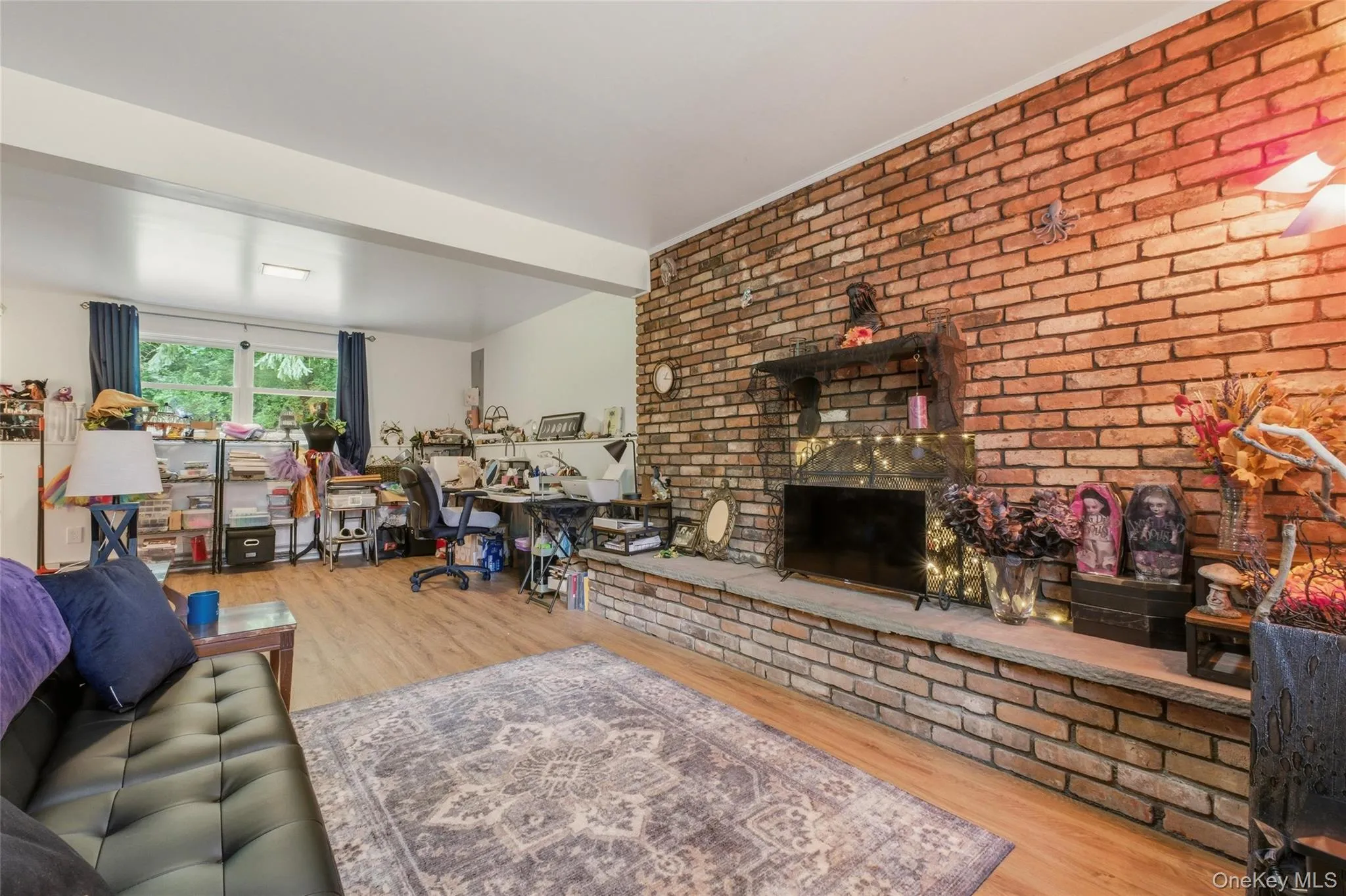 Exposed brick wall featuring a built-in fireplace with a stone hearth and wood mantel in finished basement Exposed brick wall featuring a built-in fireplace with a stone hearth and wood mantel in finished basement