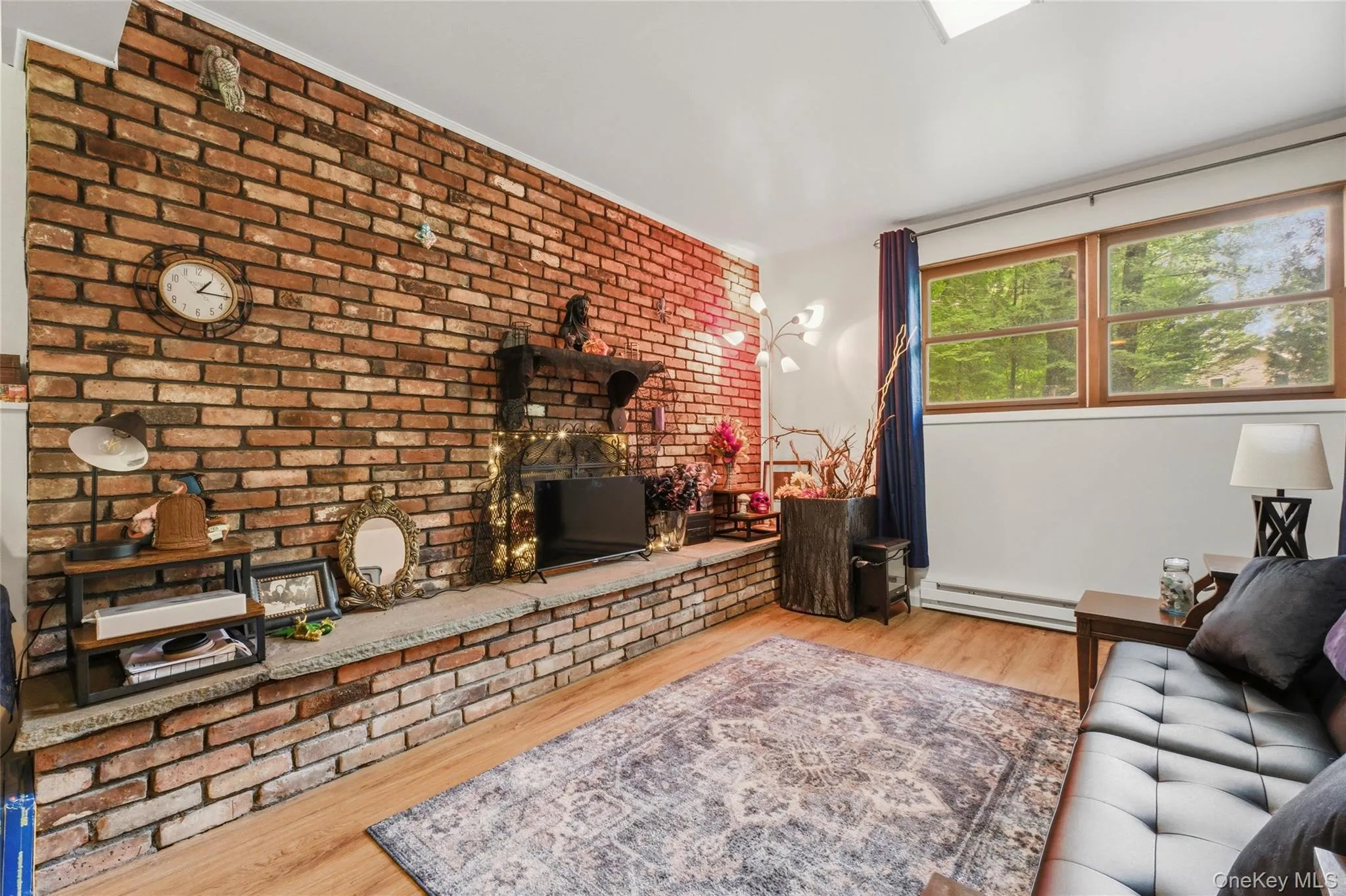 Exposed brick wall featuring a built-in fireplace with a stone hearth and wood mantel in finished basement Exposed brick wall featuring a built-in fireplace with a stone hearth and wood mantel in finished basement