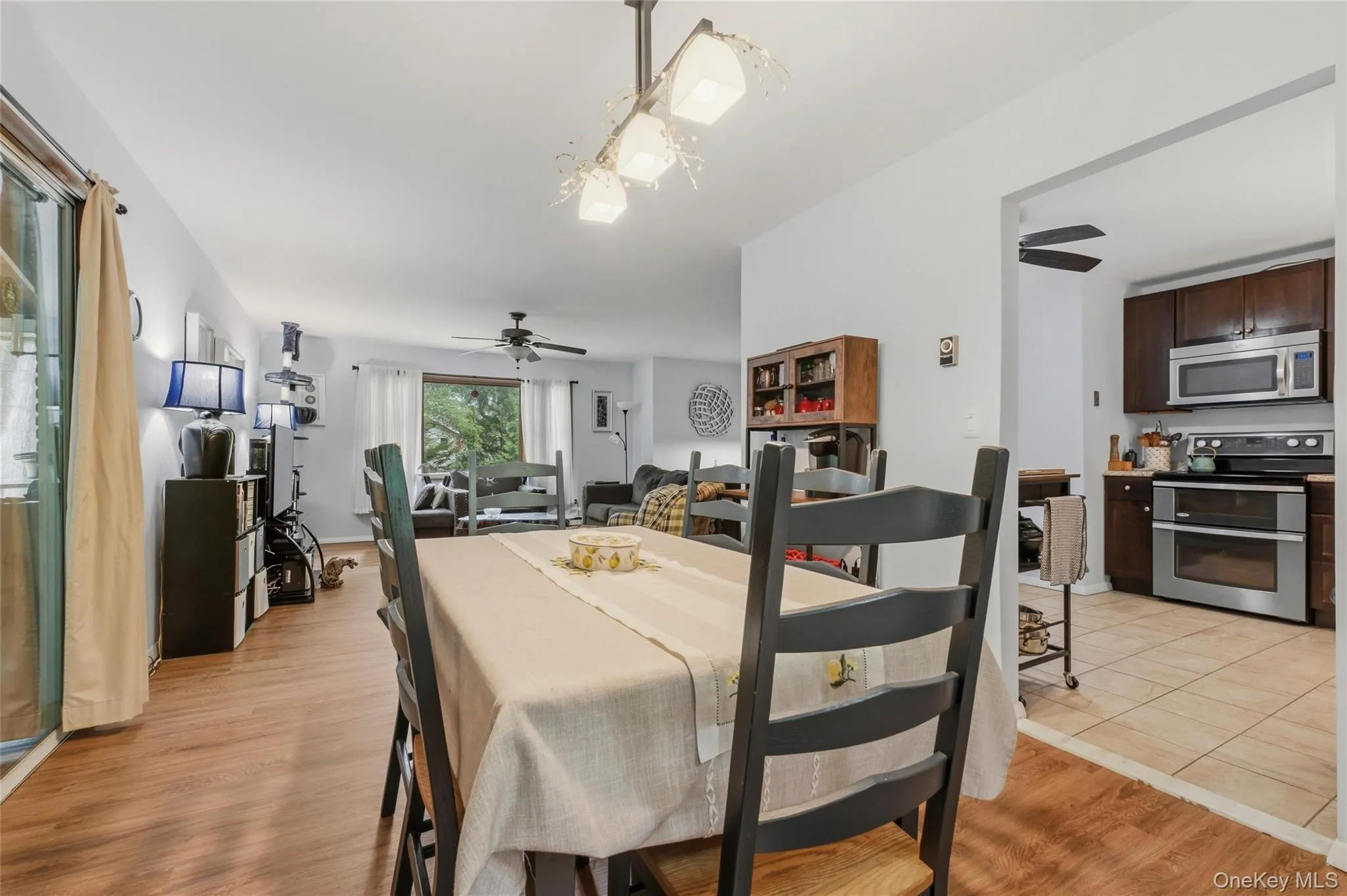 Dining area featuring wood-finish flooring and a large window leading to the kitchen, living room and deck Dining area featuring wood-finish flooring and a large window leading to the kitchen, living room and deck
