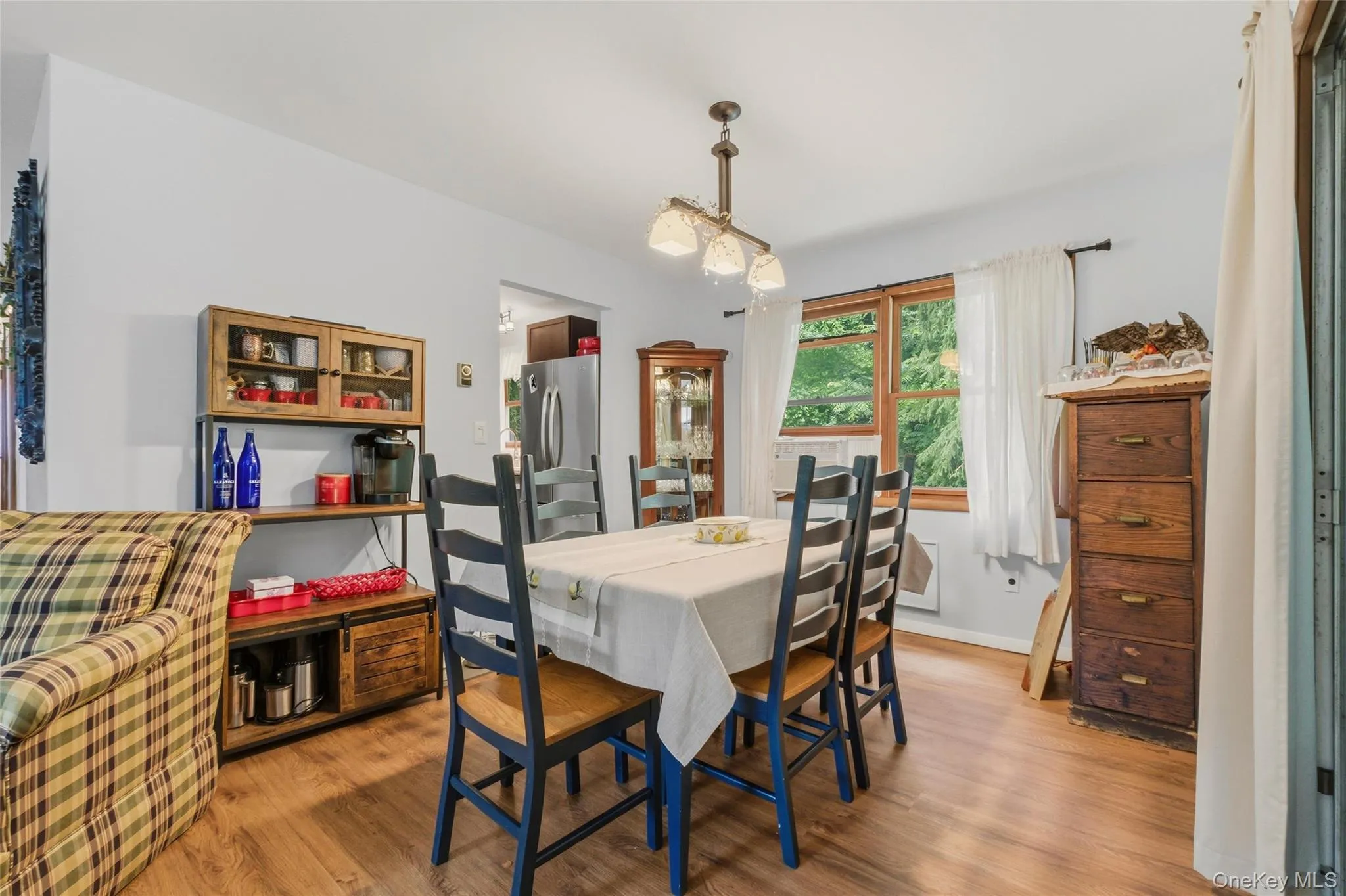 Dining area featuring wood-finish flooring and a large window leading to the kitchen Dining area featuring wood-finish flooring and a large window leading to the kitchen