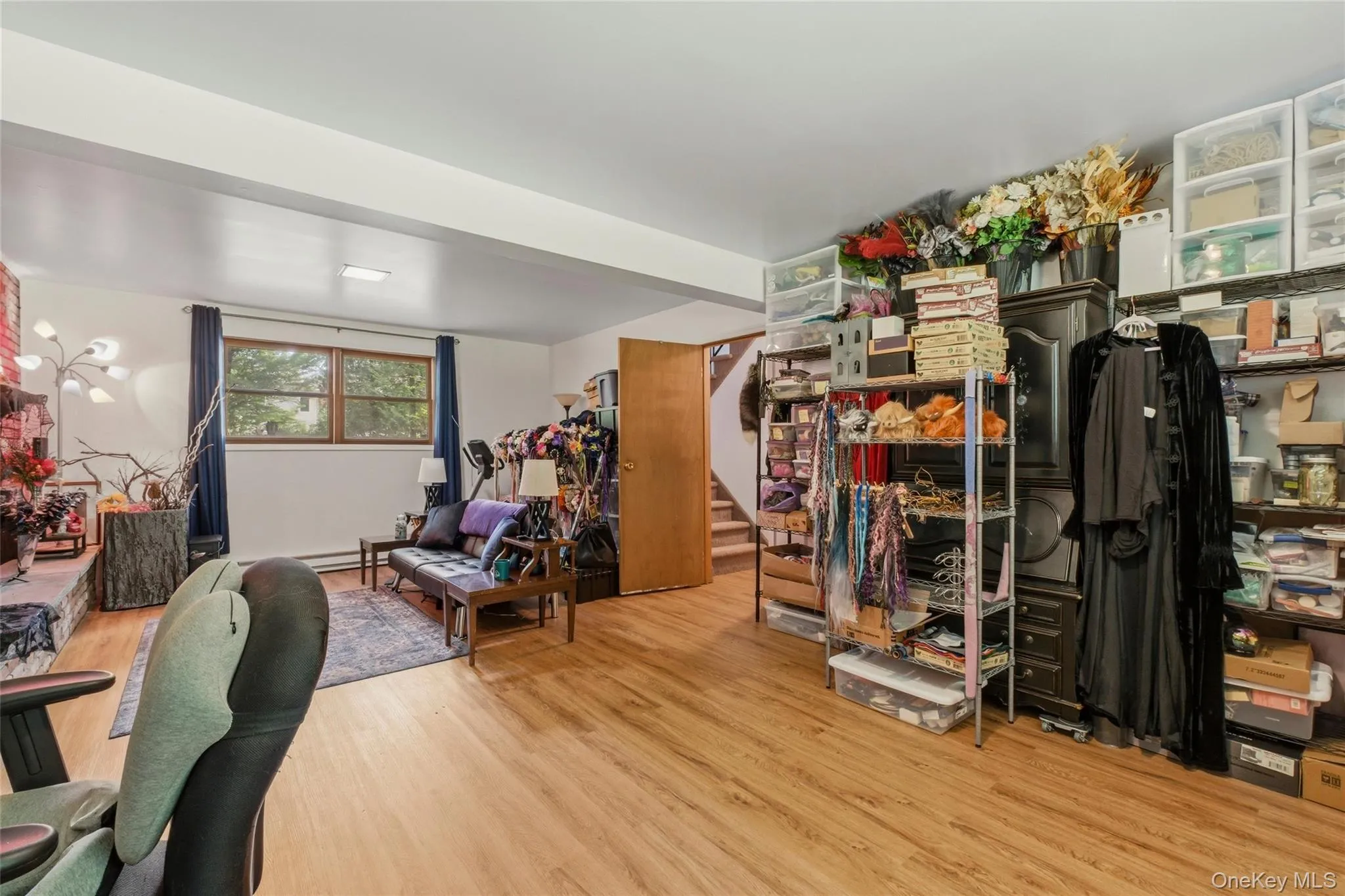 Bright finished basement room featuring wood-finish flooring, white walls, and a recessed ceiling light Bright finished basement room featuring wood-finish flooring, white walls, and a recessed ceiling light