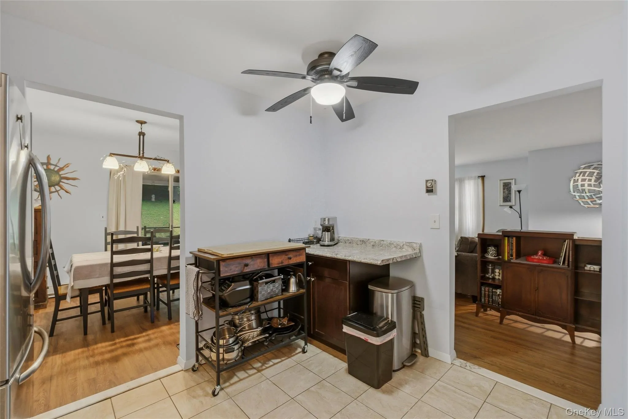Modern kitchen featuring rich wood cabinetry, light-toned countertops, and a full suite of stainless steel appliances and window Modern kitchen featuring rich wood cabinetry, light-toned countertops, and a full suite of stainless steel appliances and window