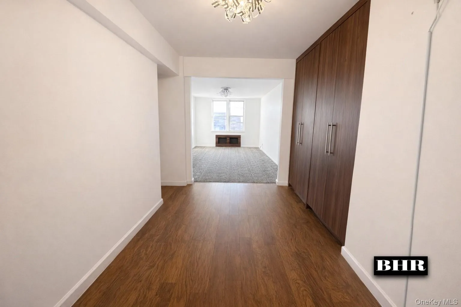 Corridor featuring dark wood-style flooring and a chandelier Corridor featuring dark wood-style flooring and a chandelier