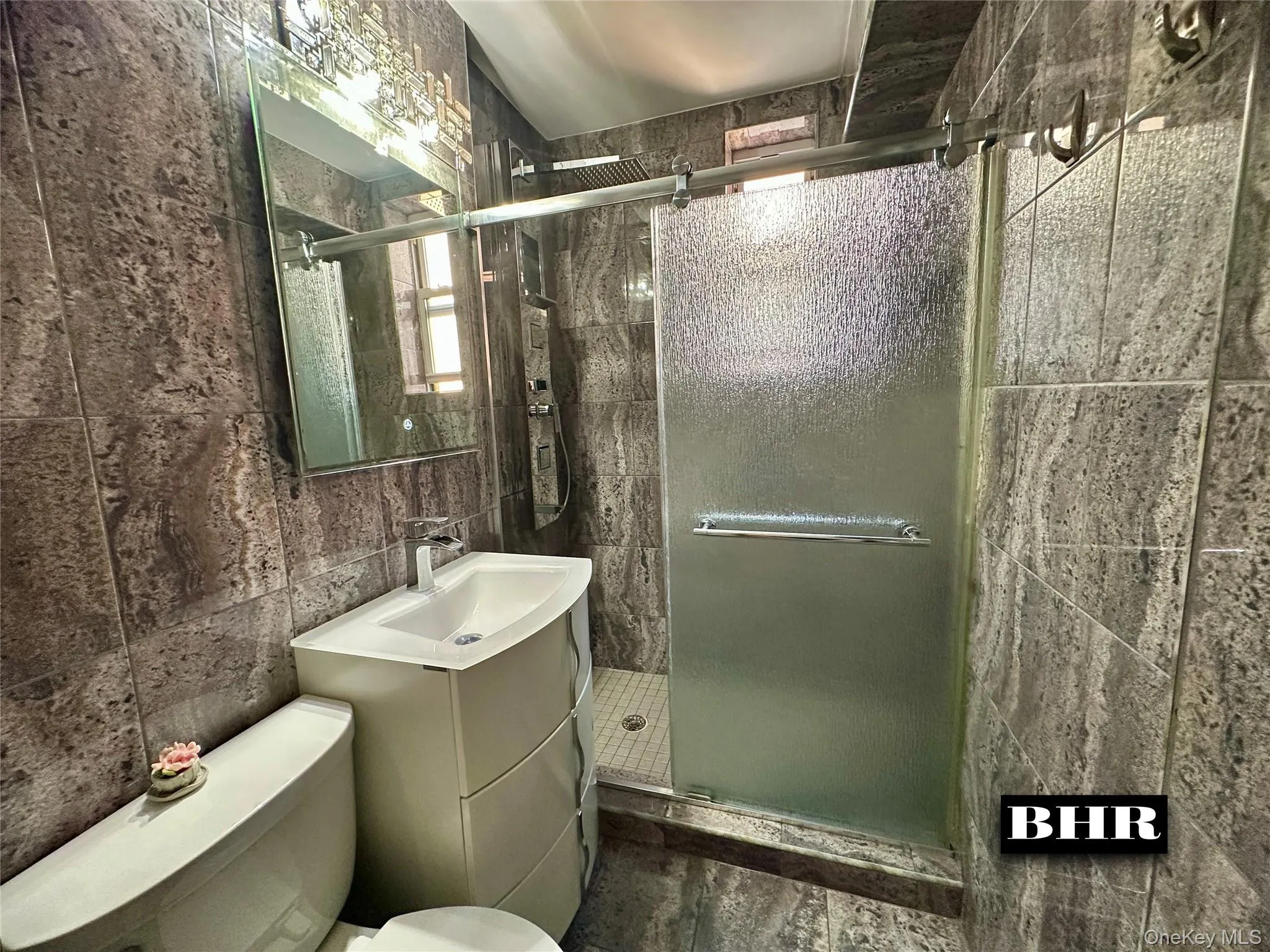 Bathroom featuring a stall shower, tile walls, and vanity Bathroom featuring a stall shower, tile walls, and vanity