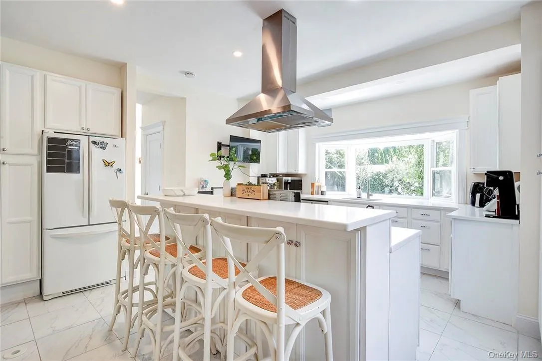 Renovated Kitchen with seating at island, white cabinetry, and light marble finish flooring Renovated Kitchen with seating at island, white cabinetry, and light marble finish flooring
