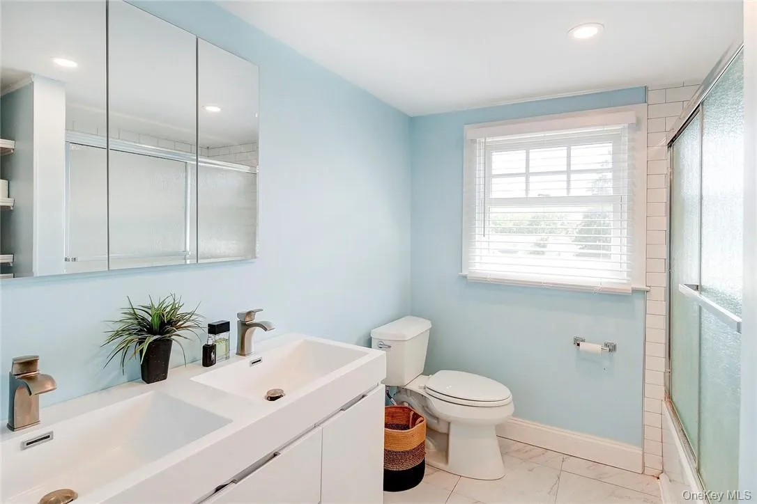 Full updated bathroom with double vanity, recessed lighting, and enclosed tub / shower combo Full updated bathroom with double vanity, recessed lighting, and enclosed tub / shower combo