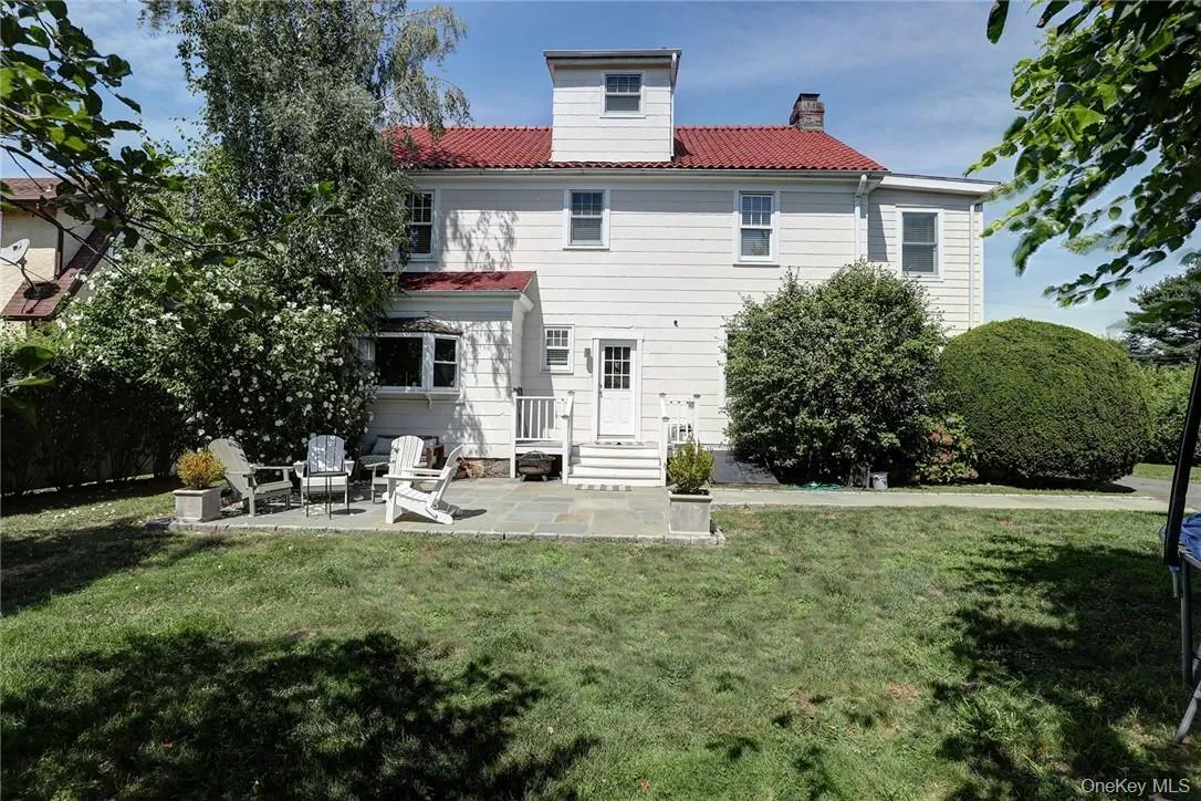 Rear view of house with patio and tiled roof. Rear view of house with patio and tiled roof.