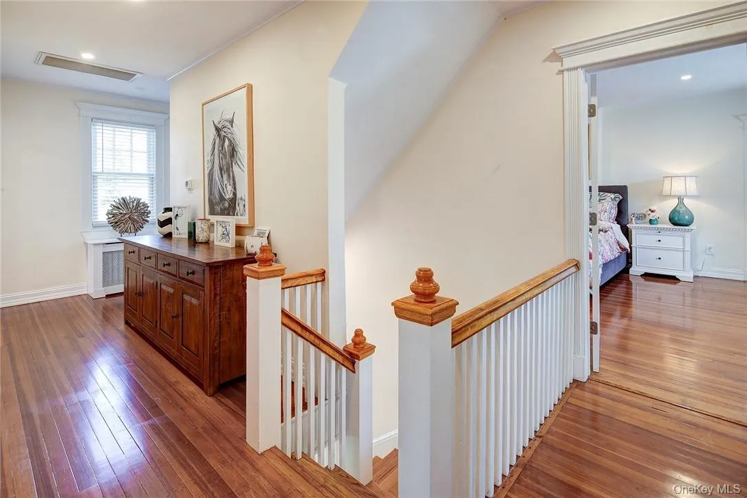Hallway featuring hardwood floors, an upstairs landing, and recessed lighting Hallway featuring hardwood floors, an upstairs landing, and recessed lighting