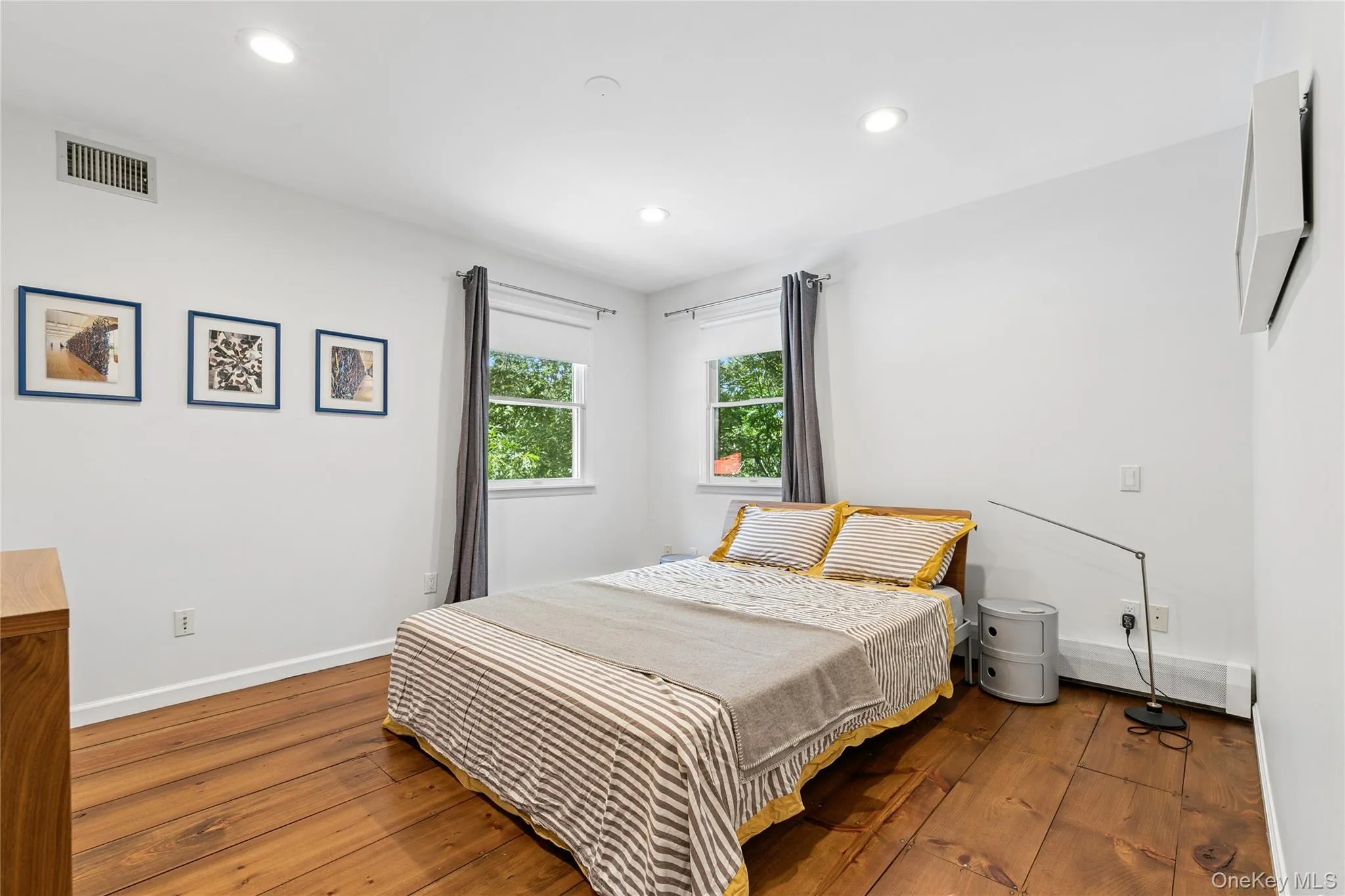 Bedroom featuring wood-finish flooring, recessed lighting, and two windows with exterior views Bedroom featuring wood-finish flooring, recessed lighting, and two windows with exterior views