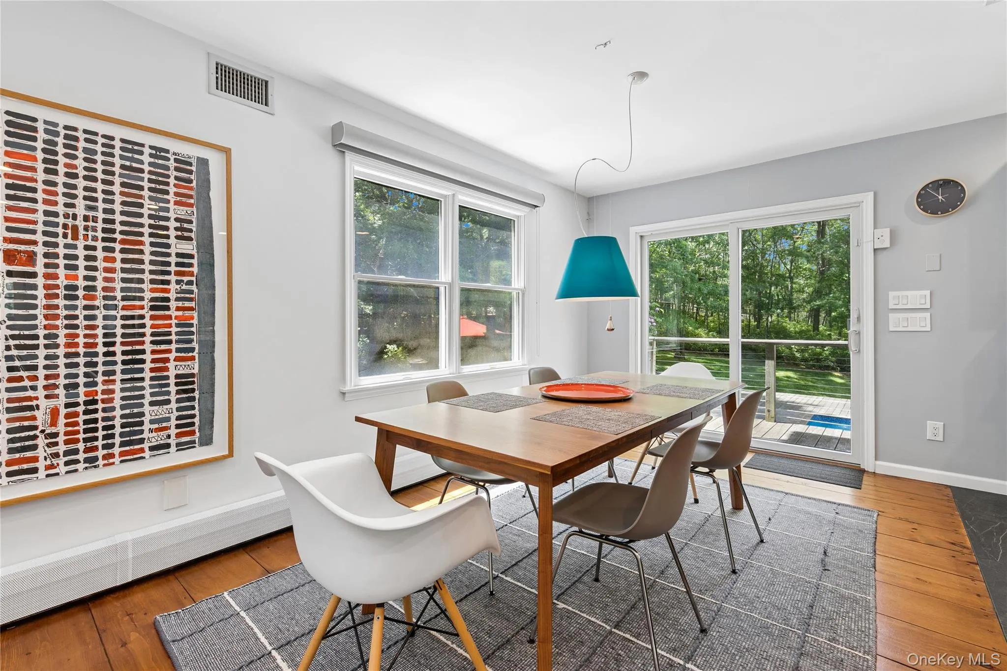Dining area featuring wood-finish flooring, a contemporary pendant light fixture, and a sliding glass door providing access to an exterior deck Dining area featuring wood-finish flooring, a contemporary pendant light fixture, and a sliding glass door providing access to an exterior deck