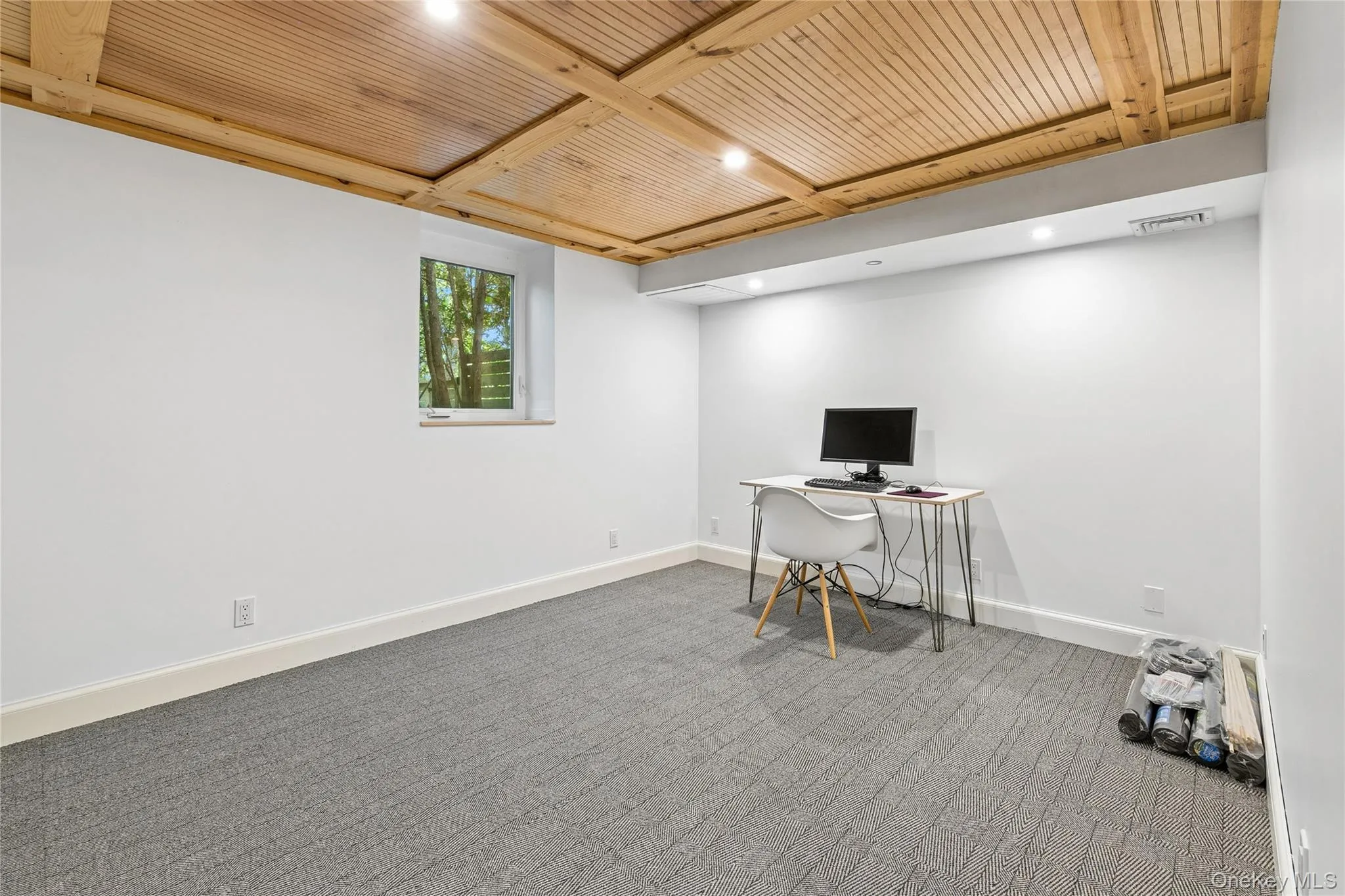 Den/Office featuring a wood-finish coffered ceiling, recessed lighting, and a single window with exterior landscaping visible Den/Office featuring a wood-finish coffered ceiling, recessed lighting, and a single window with exterior landscaping visible