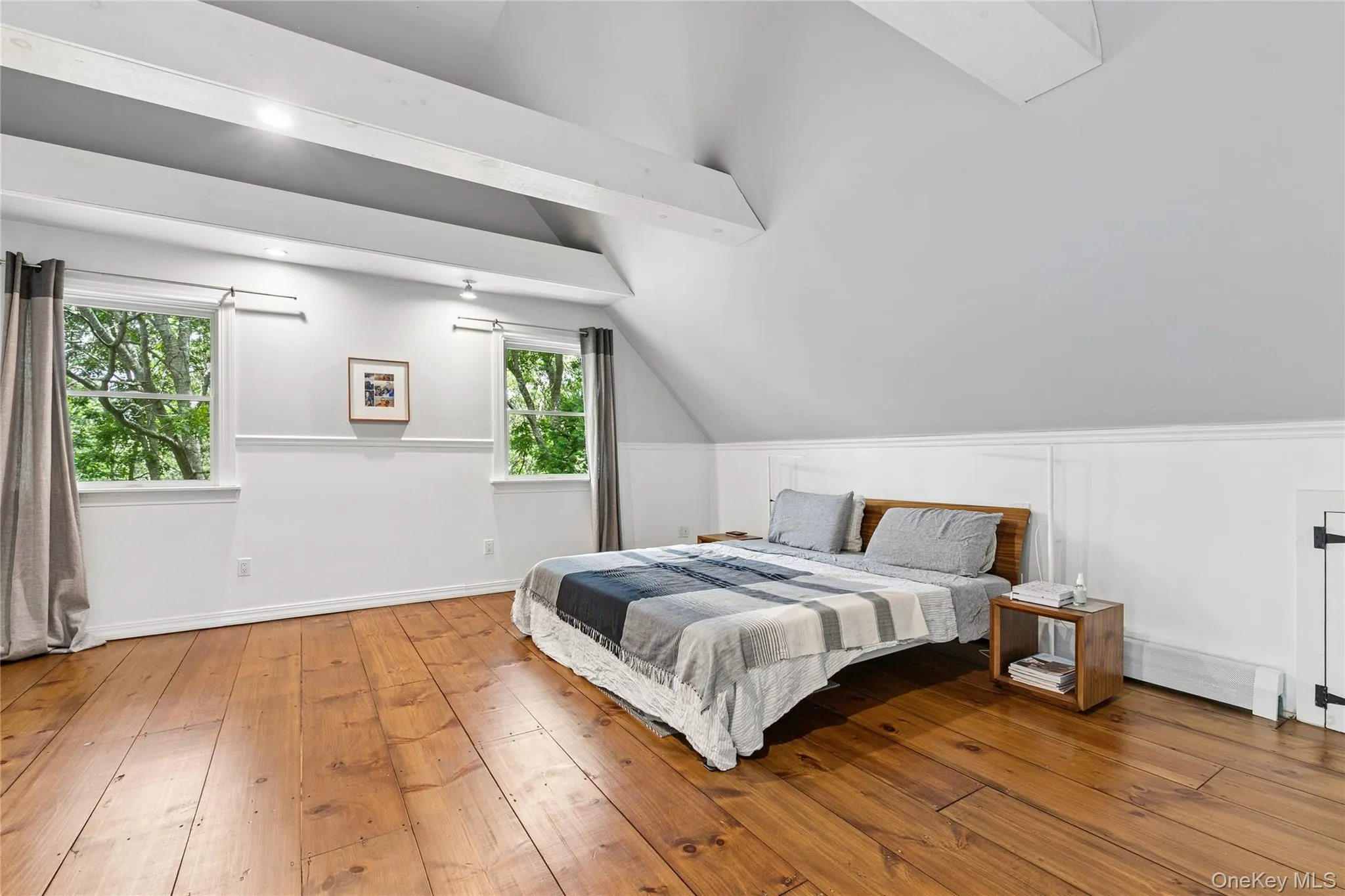Spacious room featuring exposed ceiling beams, two windows, and wide plank wood flooring Spacious room featuring exposed ceiling beams, two windows, and wide plank wood flooring