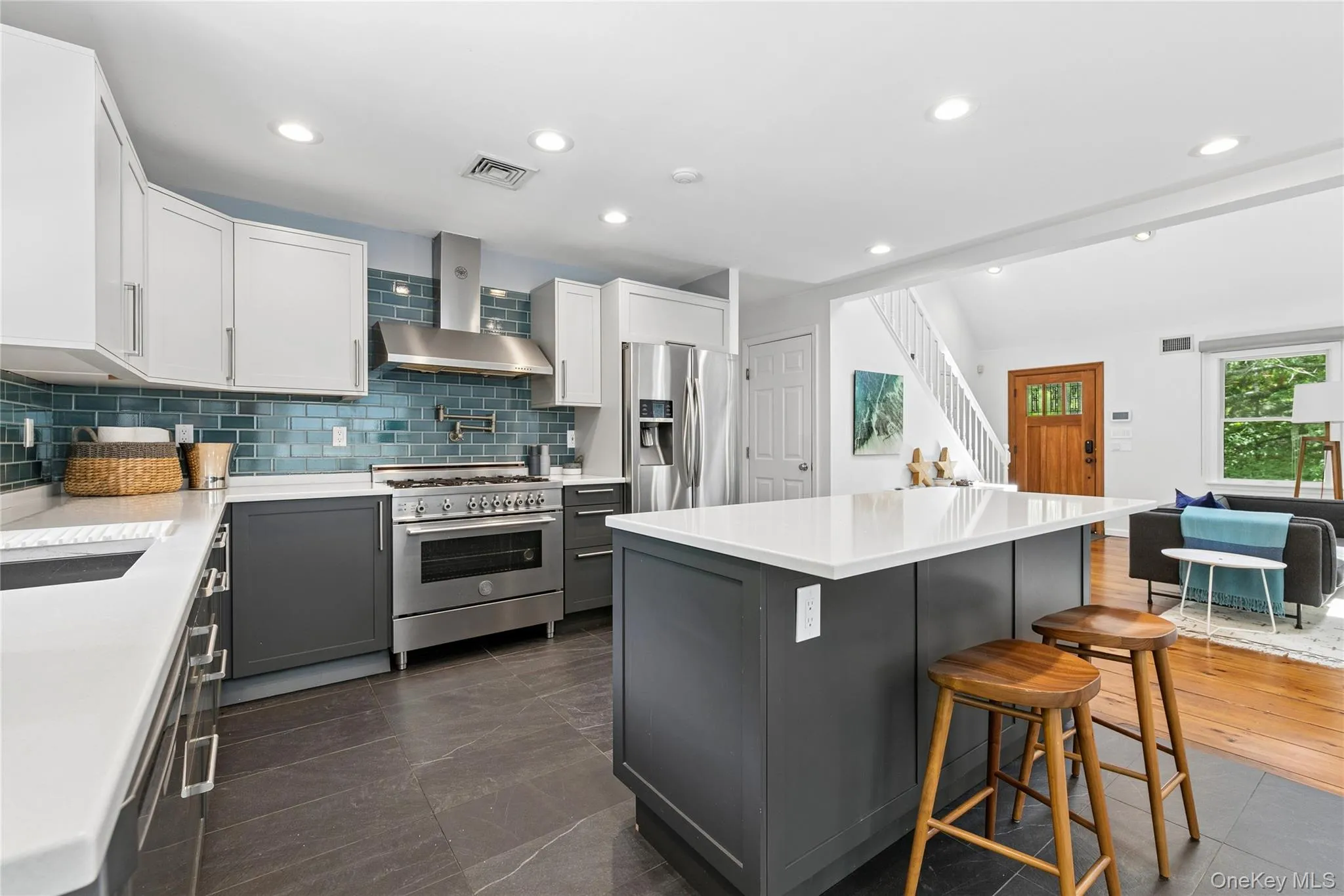 Modern kitchen featuring a large center island, contrasting two-tone cabinetry, stainless steel appliances, a tile backsplash, and recessed lighting Modern kitchen featuring a large center island, contrasting two-tone cabinetry, stainless steel appliances, a tile backsplash, and recessed lighting