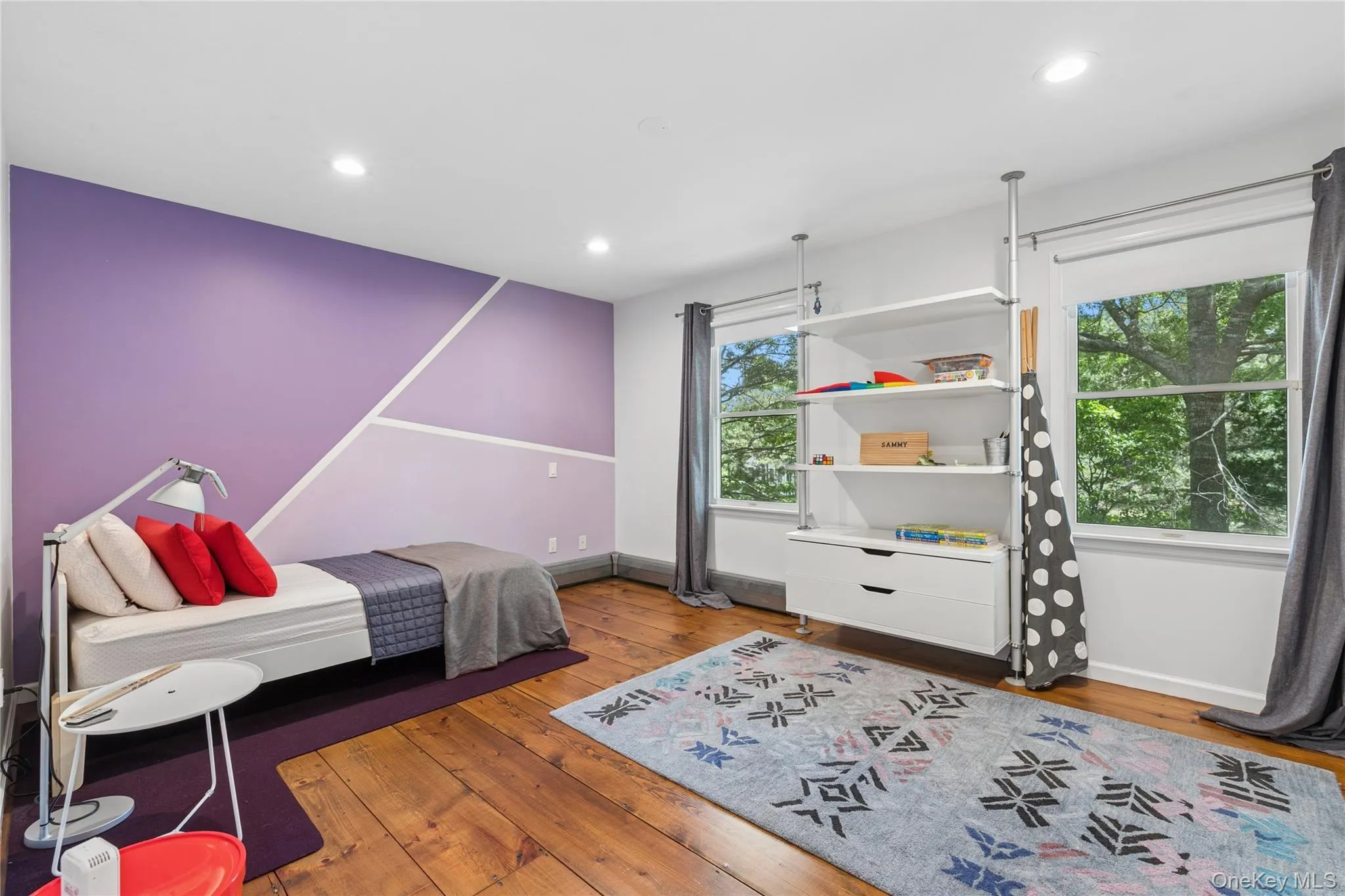 Hardwood flooring in a spacious room featuring two large windows, recessed lighting, and a built-in shelving unit with drawer storage Hardwood flooring in a spacious room featuring two large windows, recessed lighting, and a built-in shelving unit with drawer storage