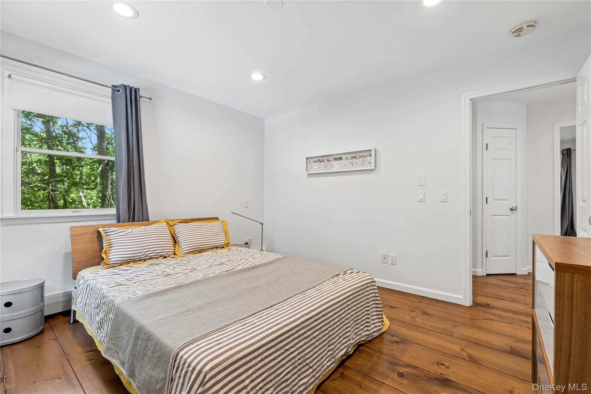 Spacious room featuring wood-finish flooring, recessed lighting, and a large window Spacious room featuring wood-finish flooring, recessed lighting, and a large window