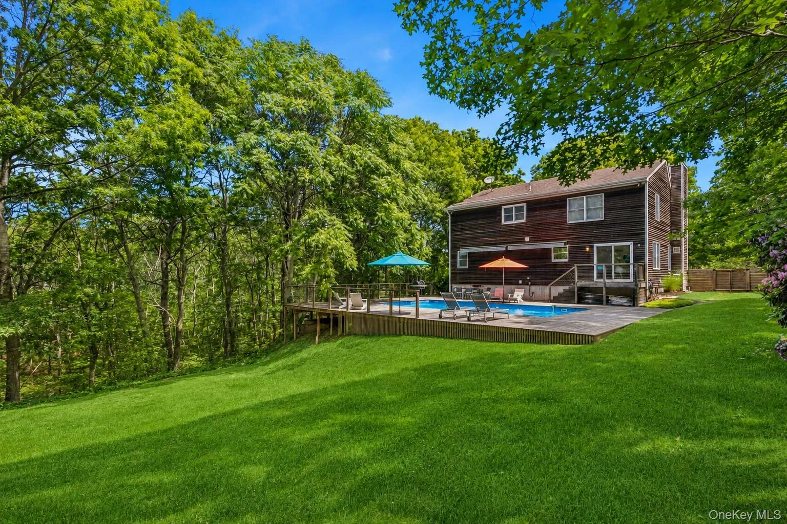 Expansive backyard featuring a large green lawn, an in-ground swimming pool, and a surrounding wood deck Expansive backyard featuring a large green lawn, an in-ground swimming pool, and a surrounding wood deck
