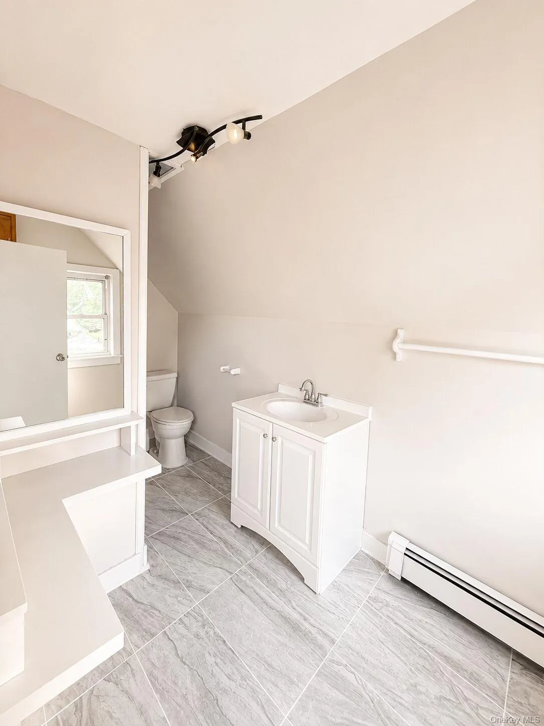 Bathroom featuring grey tile flooring, a white vanity with an integrated sink, and track lighting Bathroom featuring grey tile flooring, a white vanity with an integrated sink, and track lighting