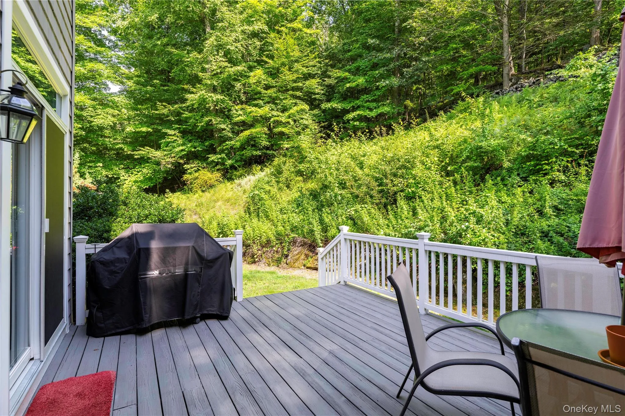 Spacious outdoor deck featuring gray composite decking, white baluster railing, and direct access to the interior via a sliding glass door Spacious outdoor deck featuring gray composite decking, white baluster railing, and direct access to the interior via a sliding glass door