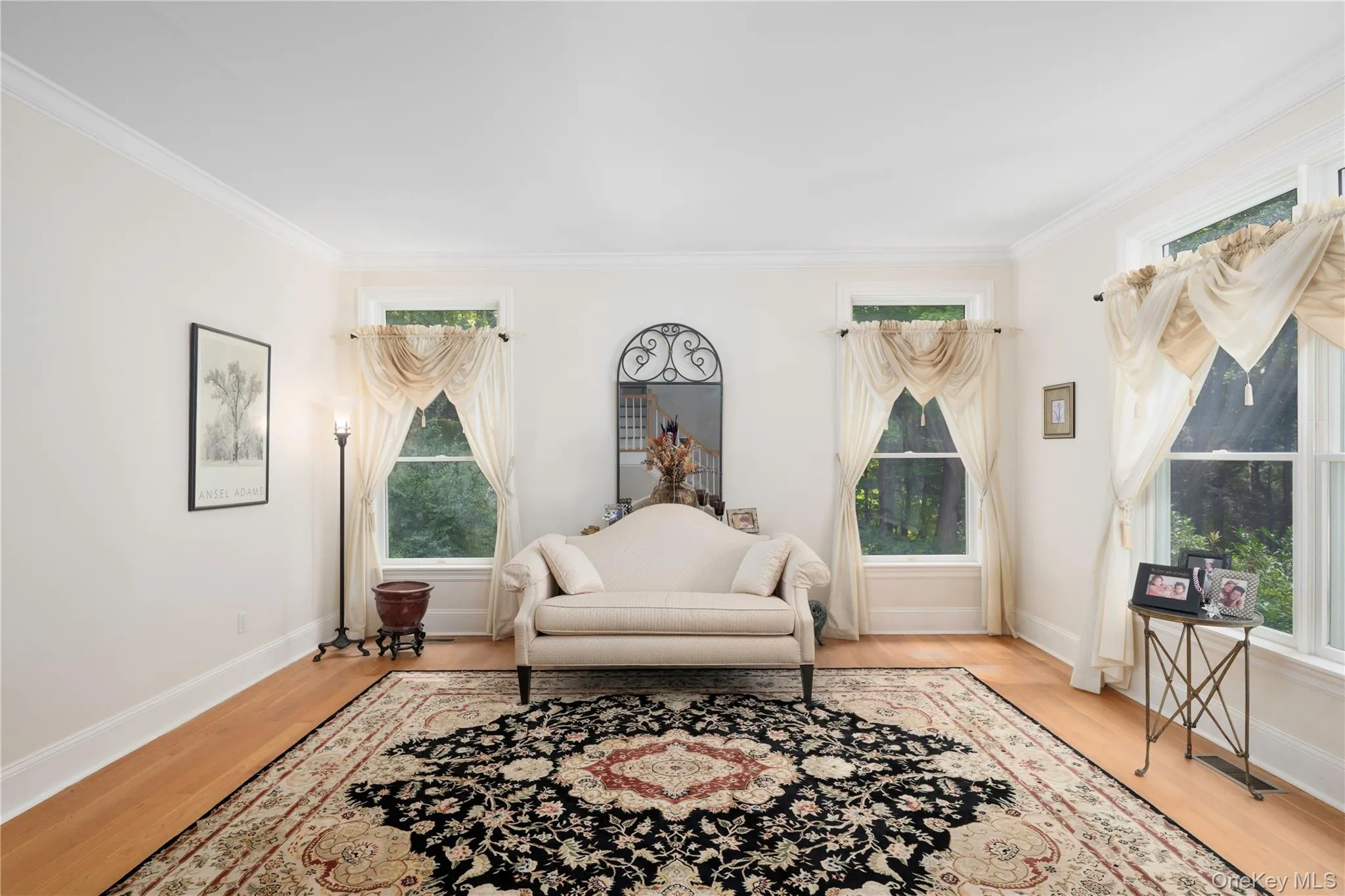 Hardwood flooring throughout this room, featuring multiple windows with ample light, crown molding, and substantial baseboards Hardwood flooring throughout this room, featuring multiple windows with ample light, crown molding, and substantial baseboards