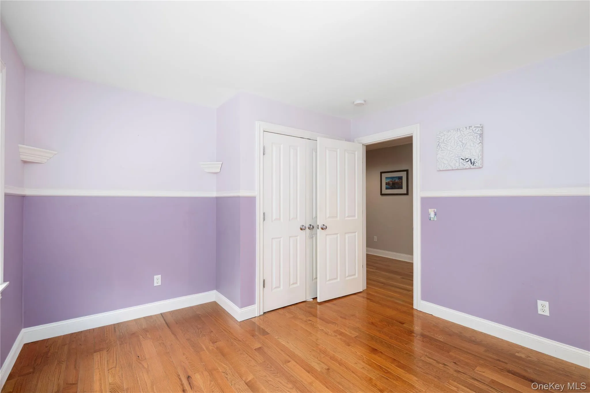 Interior room featuring wood-finish flooring and two-tone wall treatment Interior room featuring wood-finish flooring and two-tone wall treatment