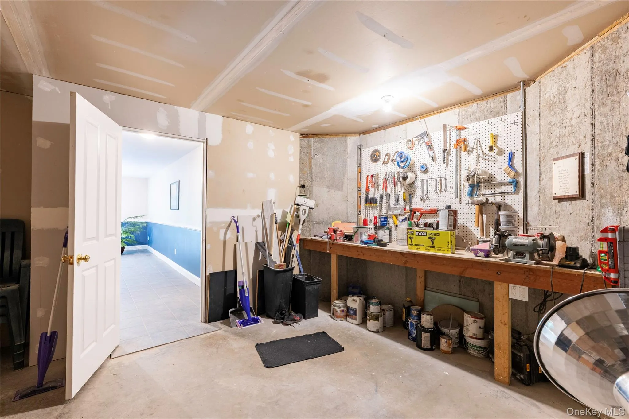 Lower level space featuring a concrete floor, built-in workbench, and pegboard storage Lower level space featuring a concrete floor, built-in workbench, and pegboard storage