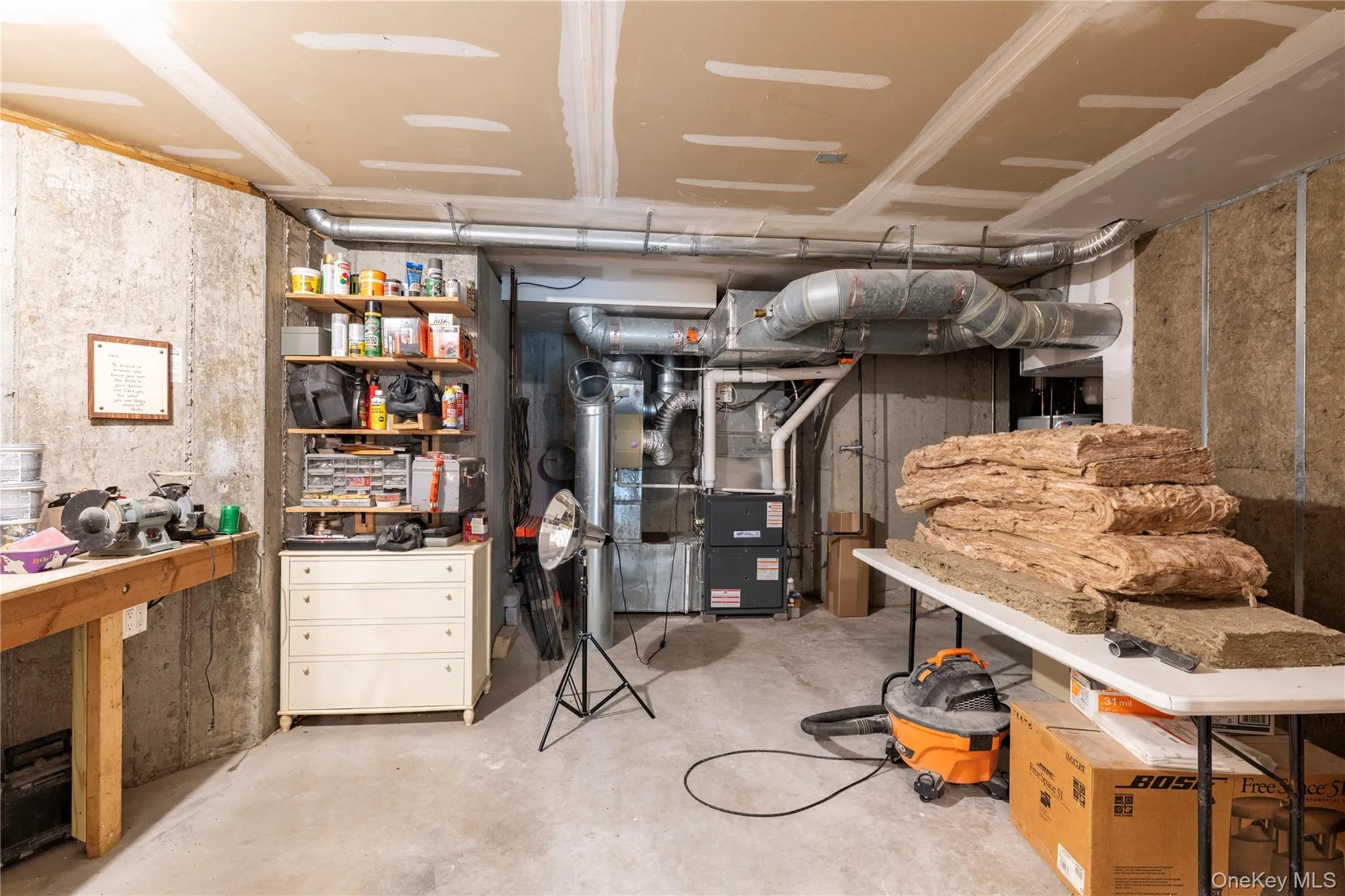 Unfinished basement featuring concrete walls and flooring, exposed ceiling joists, and visible HVAC ductwork Unfinished basement featuring concrete walls and flooring, exposed ceiling joists, and visible HVAC ductwork