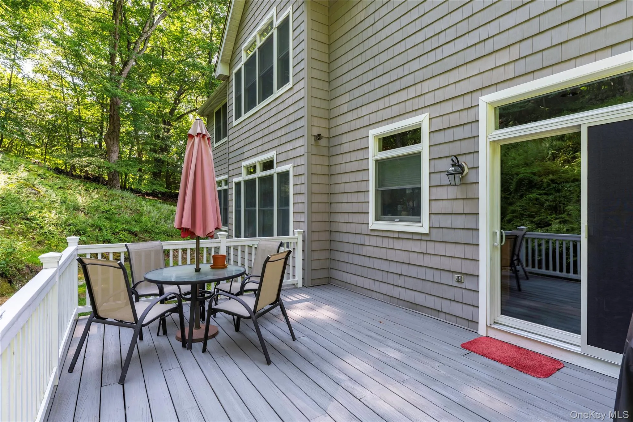 Expansive exterior deck featuring wood-finish flooring, white railing, and a sliding glass door entry Expansive exterior deck featuring wood-finish flooring, white railing, and a sliding glass door entry