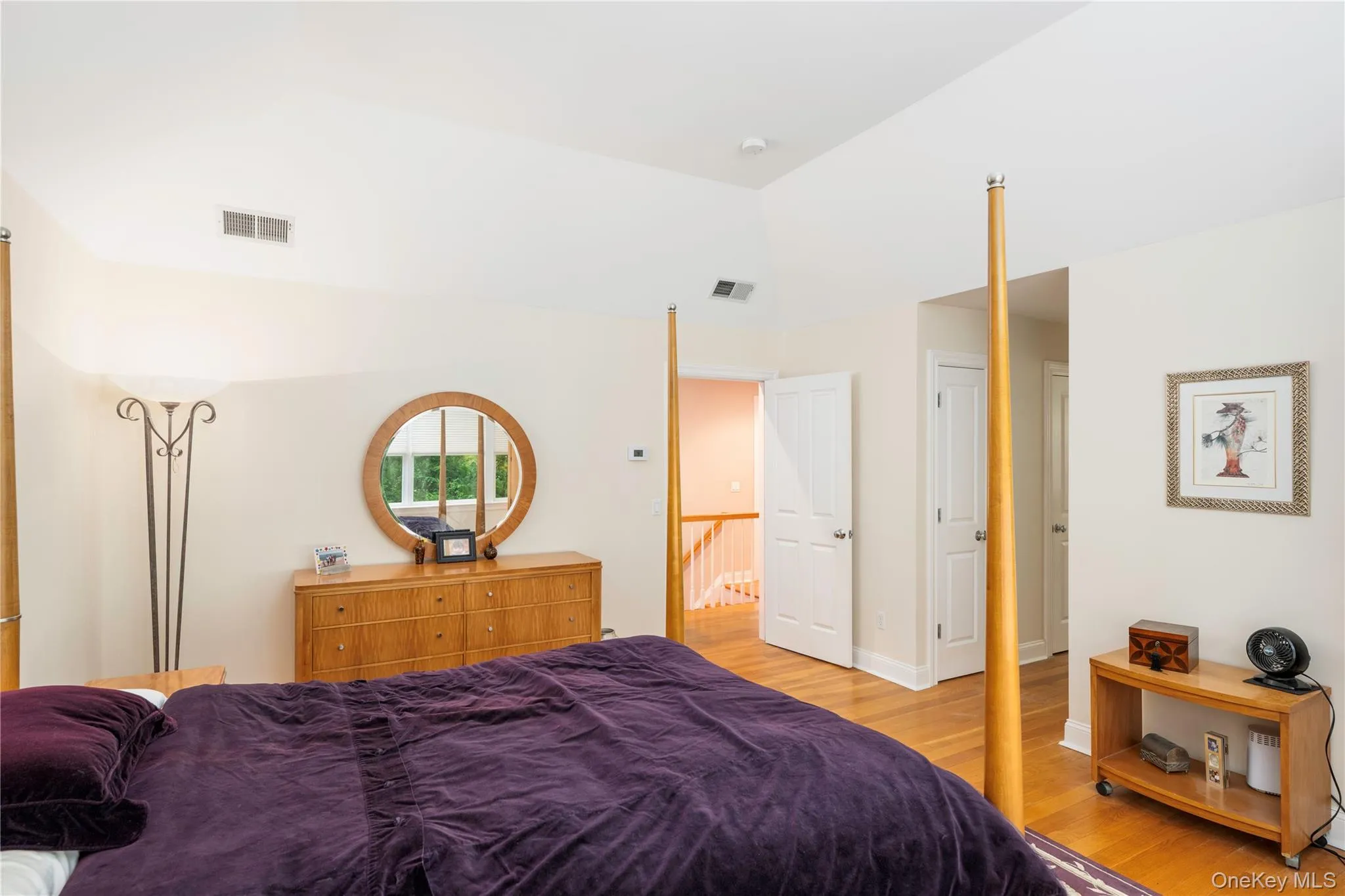 Spacious sleeping area featuring vaulted ceilings, wood-finish flooring, white paneled doors, and a built-in air vent Spacious sleeping area featuring vaulted ceilings, wood-finish flooring, white paneled doors, and a built-in air vent