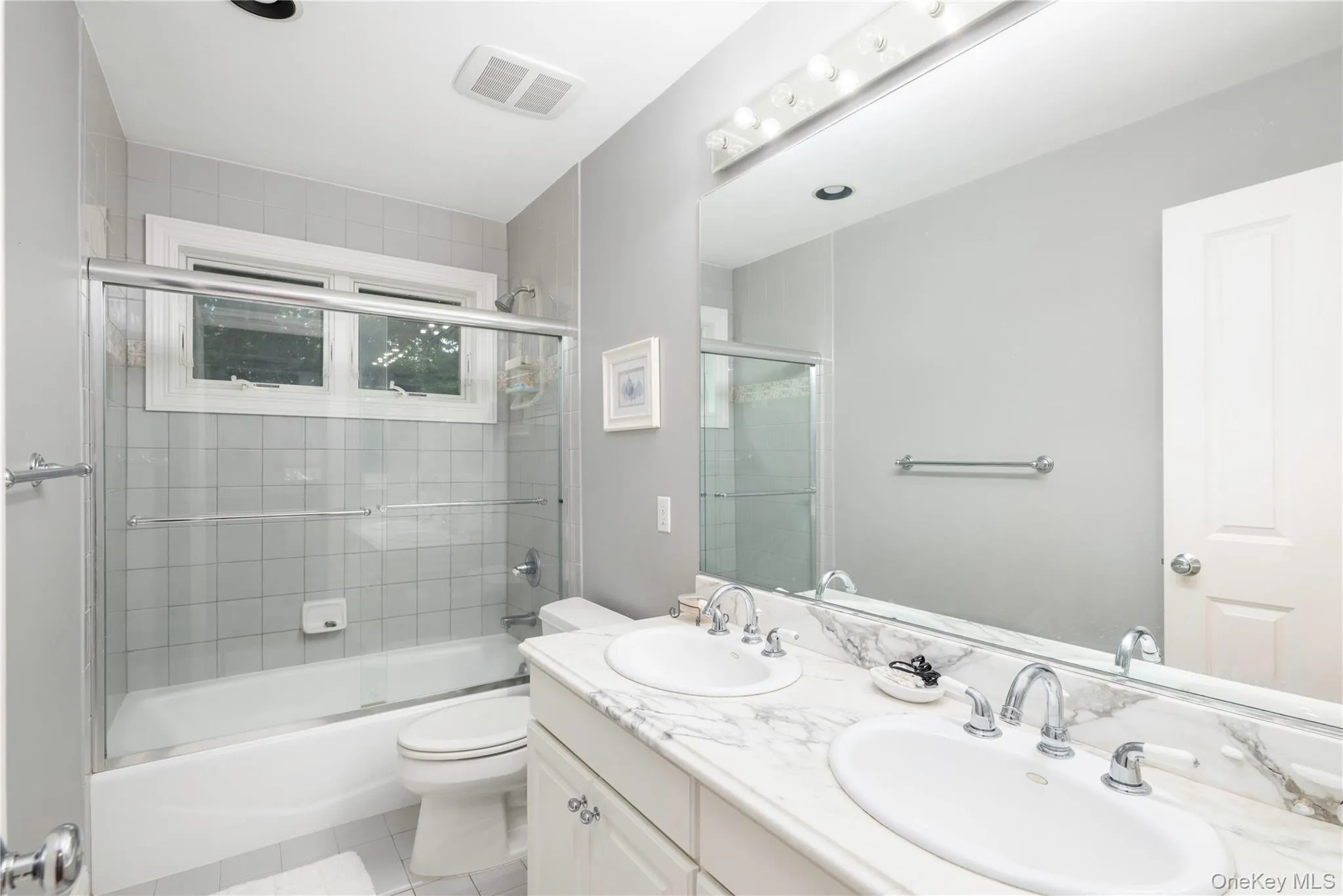 Bathroom featuring a double vanity with stone countertop, dual undermount sinks, and a full-width mirror Bathroom featuring a double vanity with stone countertop, dual undermount sinks, and a full-width mirror
