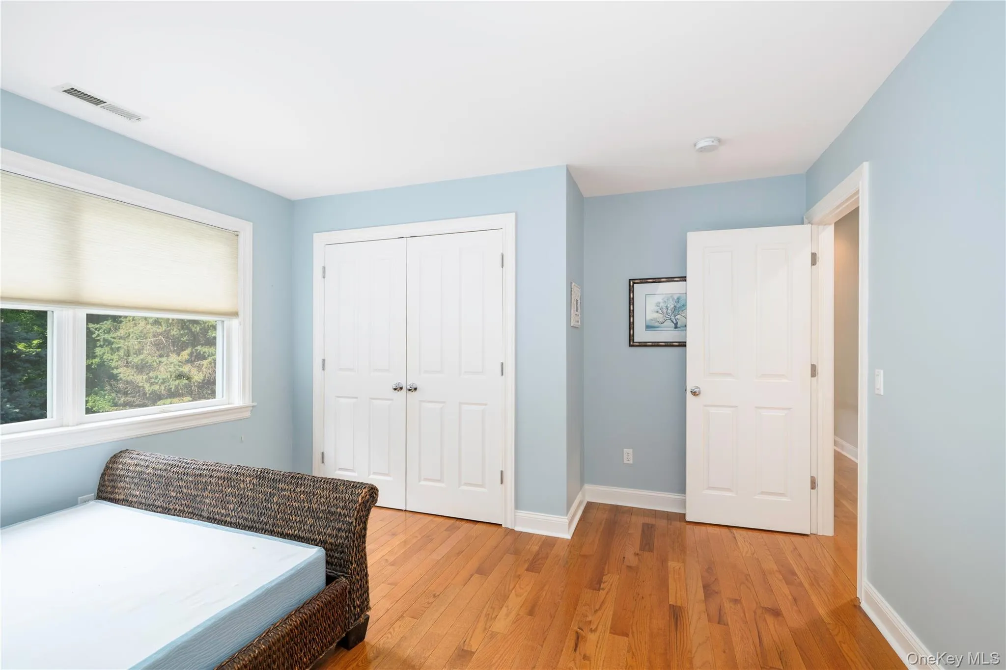 Room featuring hardwood flooring, white trim, and light blue walls Room featuring hardwood flooring, white trim, and light blue walls