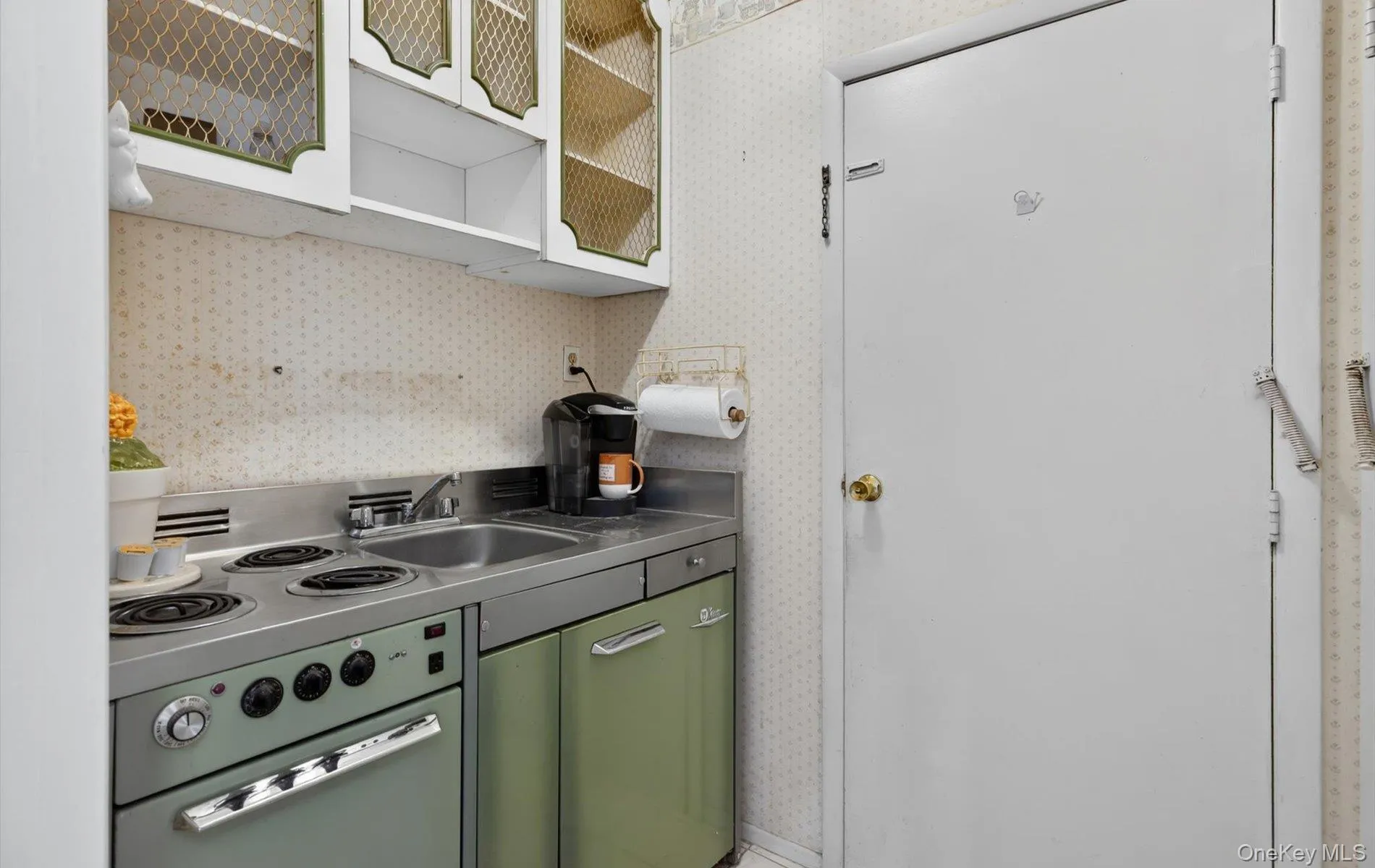Compact kitchen featuring a four-burner electric range, stainless steel sink, and light green cabinetry Compact kitchen featuring a four-burner electric range, stainless steel sink, and light green cabinetry