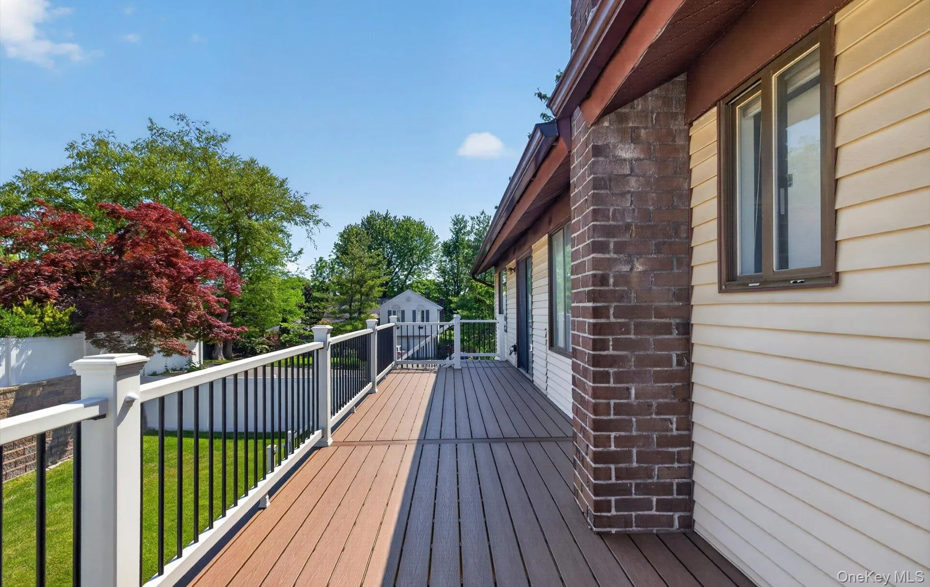 Elevated outdoor deck with composite decking and white railings featuring black balusters Elevated outdoor deck with composite decking and white railings featuring black balusters