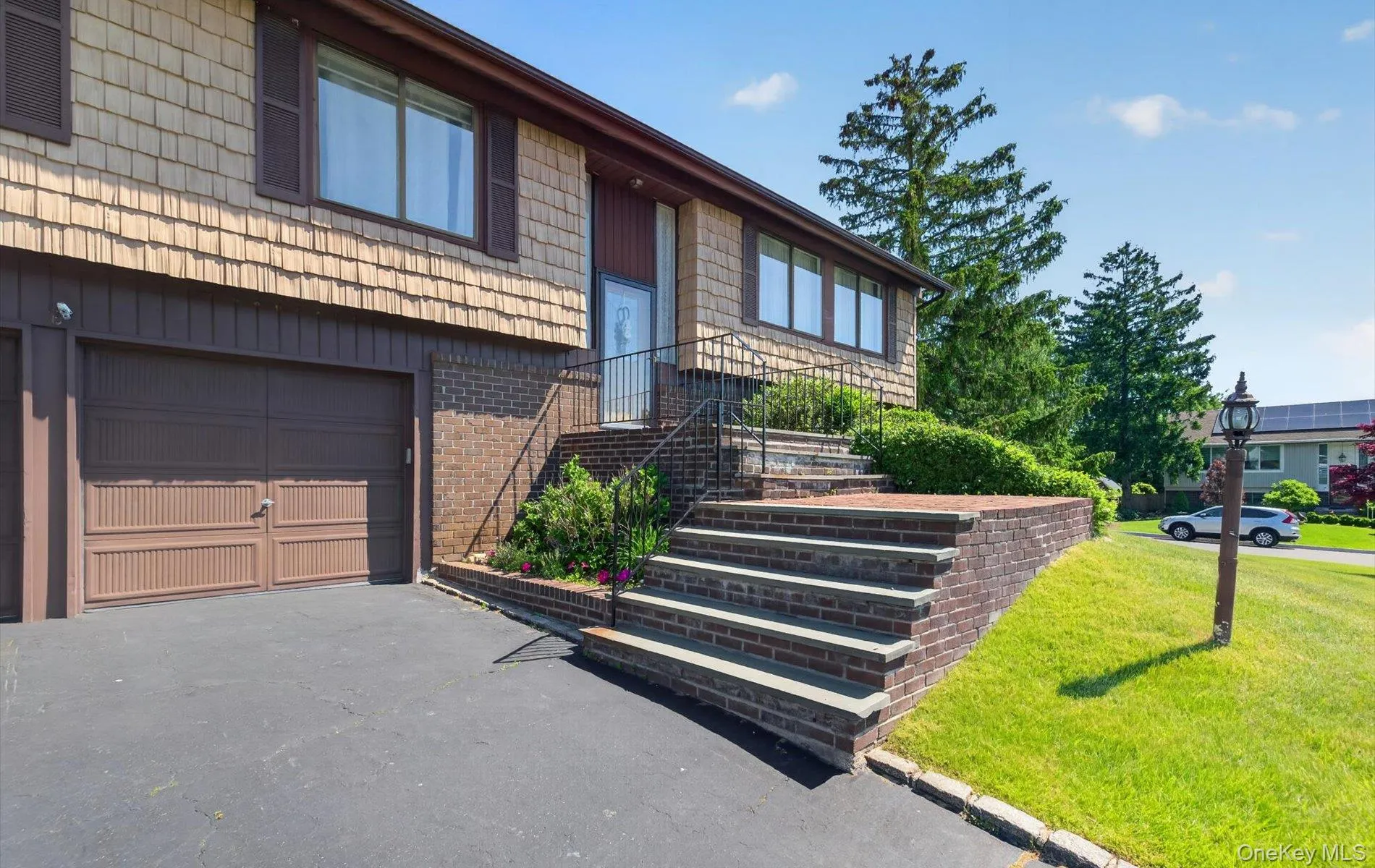 Split-level residence featuring a brown shingle and brick facade Split-level residence featuring a brown shingle and brick facade