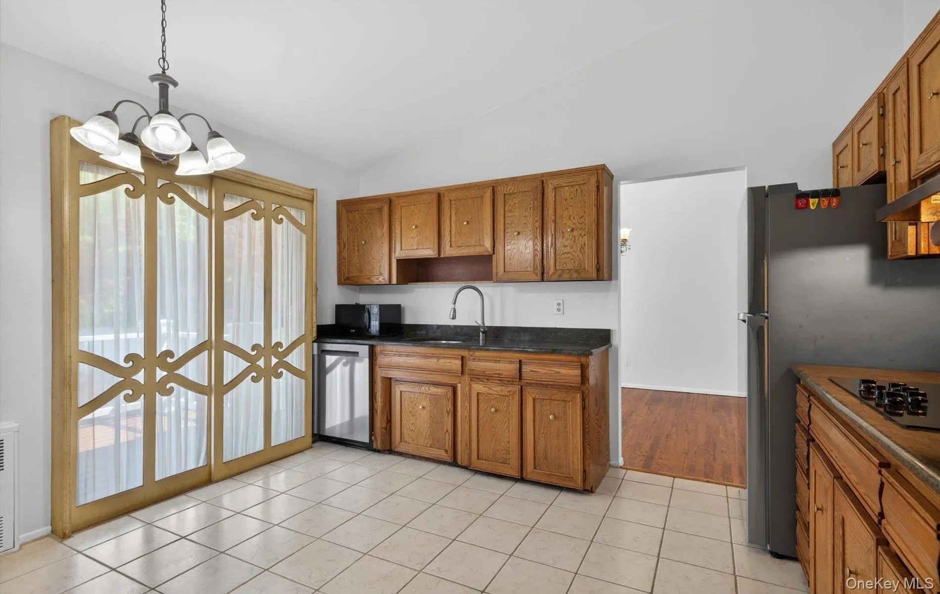 Kitchen featuring light wood cabinetry, a built-in dishwasher, and black appliances Kitchen featuring light wood cabinetry, a built-in dishwasher, and black appliances
