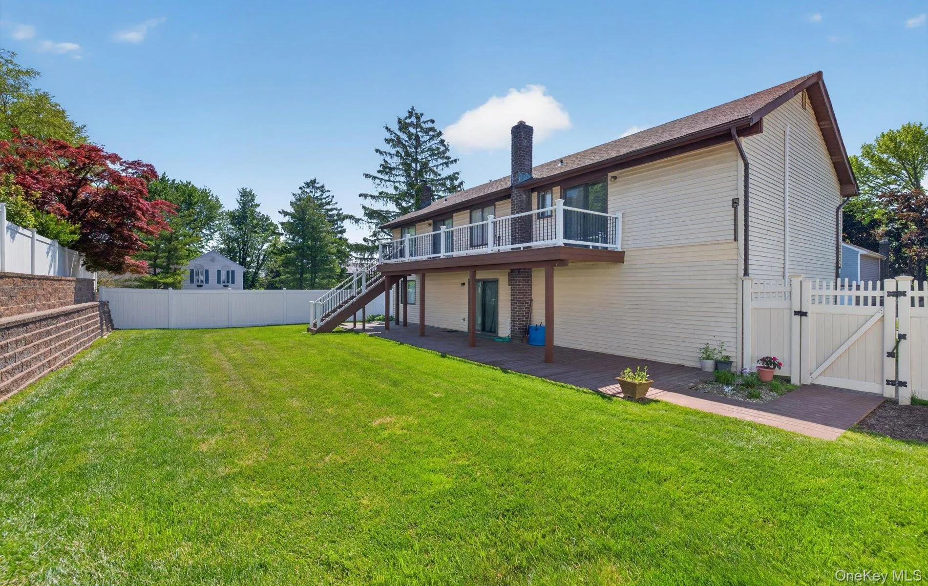 Expansive backyard featuring a manicured lawn, a multi-level retaining wall, and a full privacy fence Expansive backyard featuring a manicured lawn, a multi-level retaining wall, and a full privacy fence