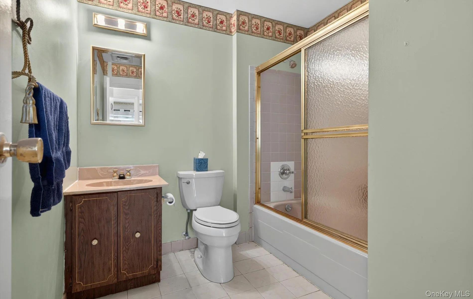 Full bathroom featuring a toilet, a vanity with a countertop sink, a framed mirror, and a tub with a sliding glass enclosure Full bathroom featuring a toilet, a vanity with a countertop sink, a framed mirror, and a tub with a sliding glass enclosure